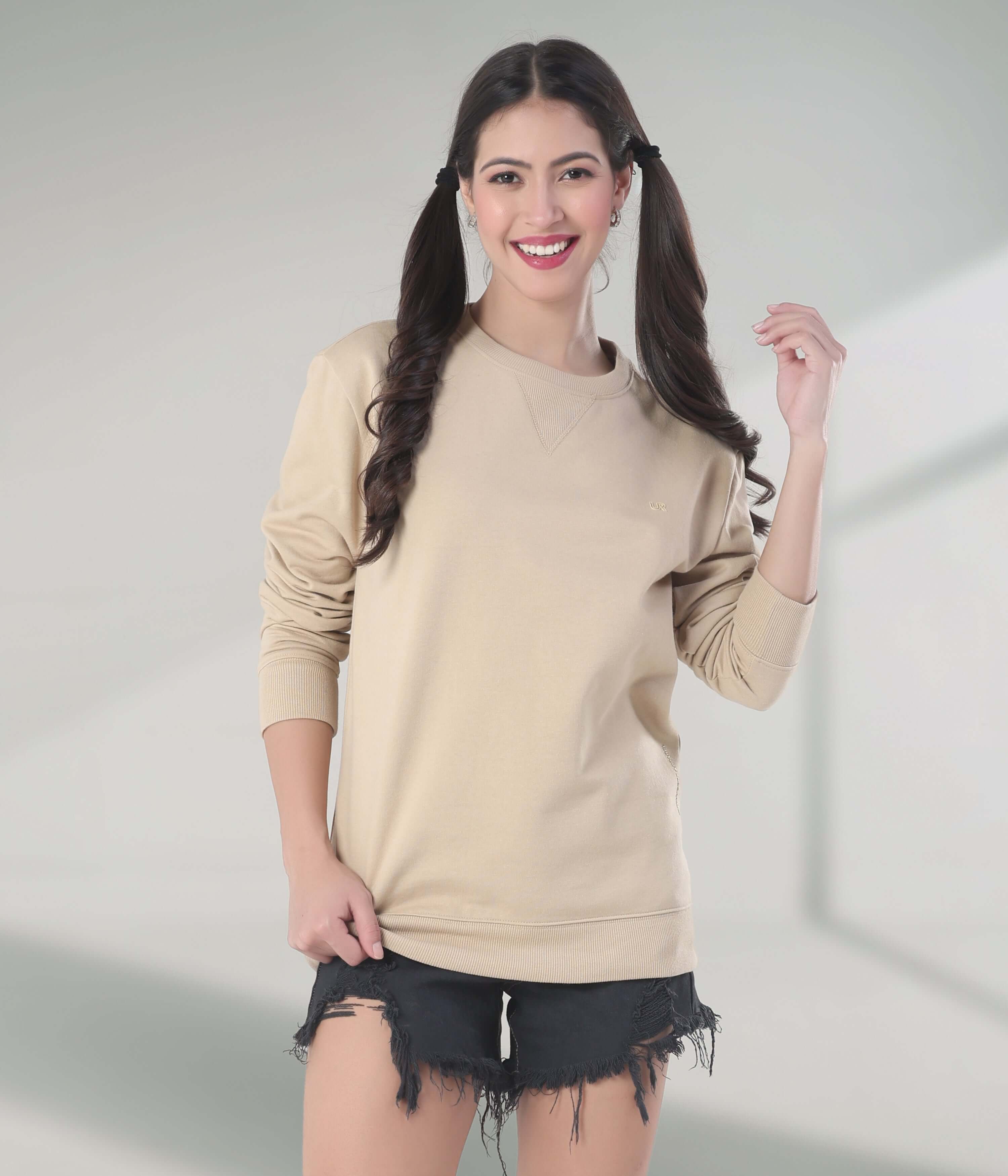 Stylish woman in beige Turms Intelligent Sweatshirt, showcasing comfort and sporty design for casual wear.