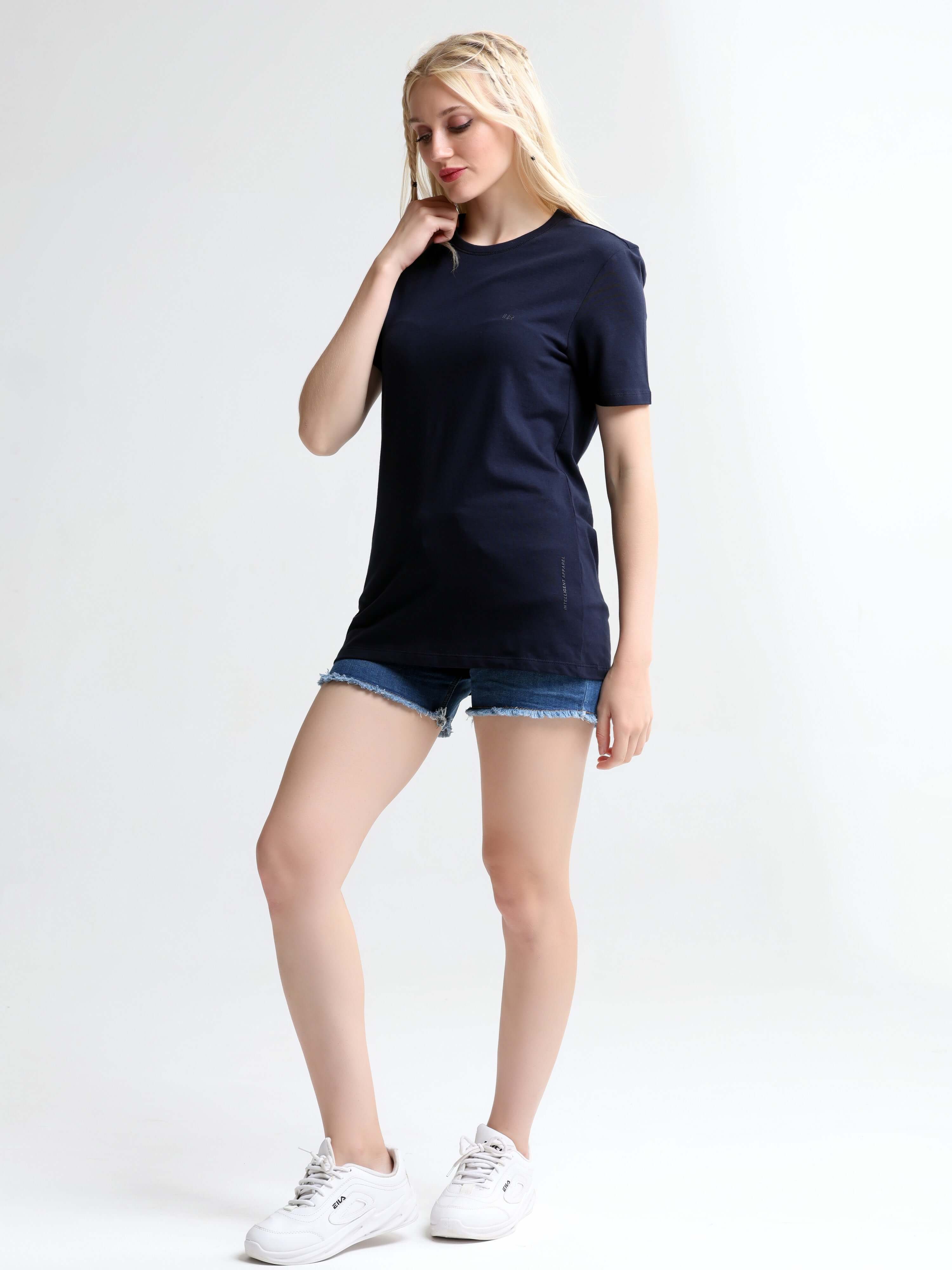 Woman wearing a Blue Mist round-neck stain-proof and odor-resistant Turms T-shirt with denim shorts and white sneakers.
