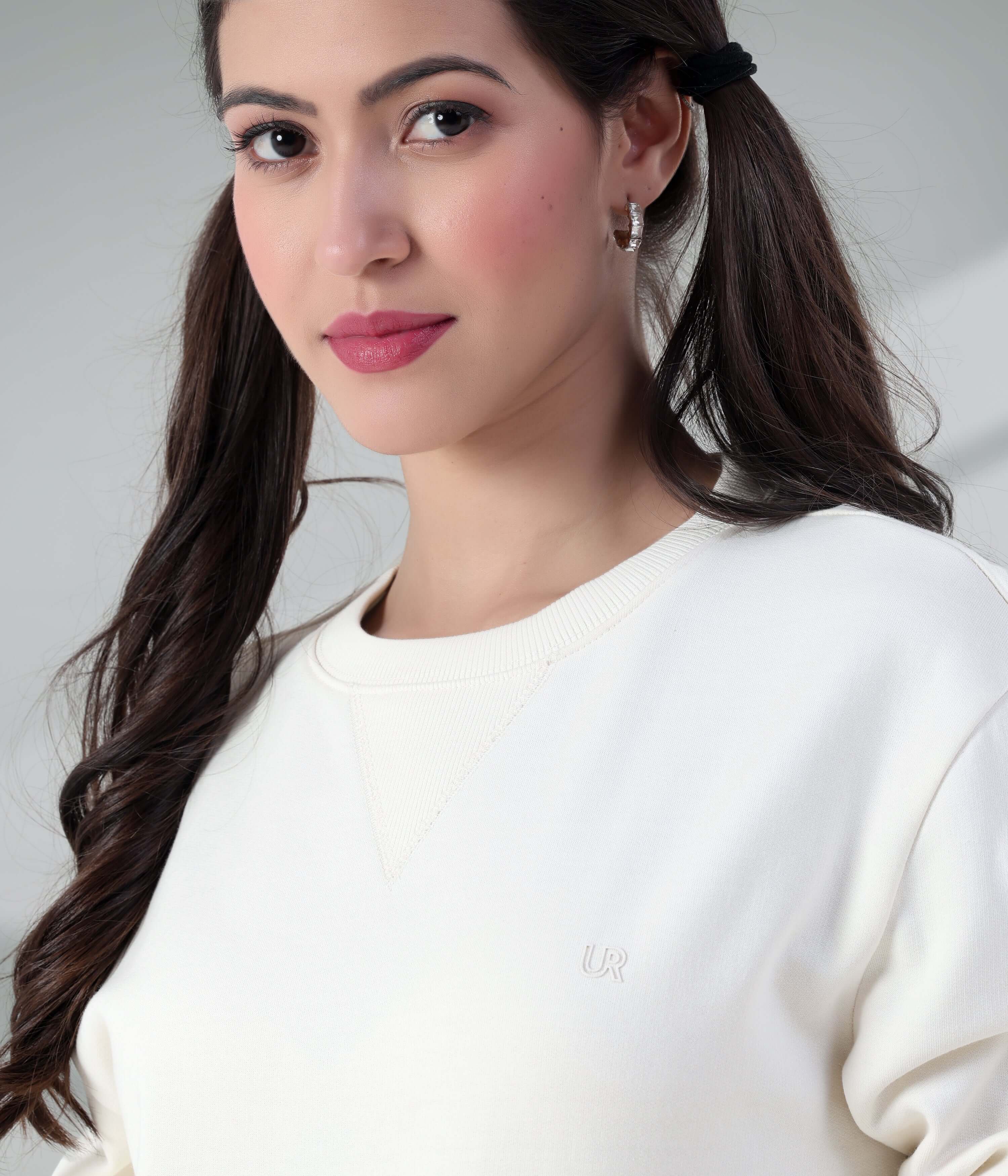 Elegant woman wearing a Turms Intelligent Sweatshirt in Artic White, showcasing a stylish V-notch neckline and soft fabric.