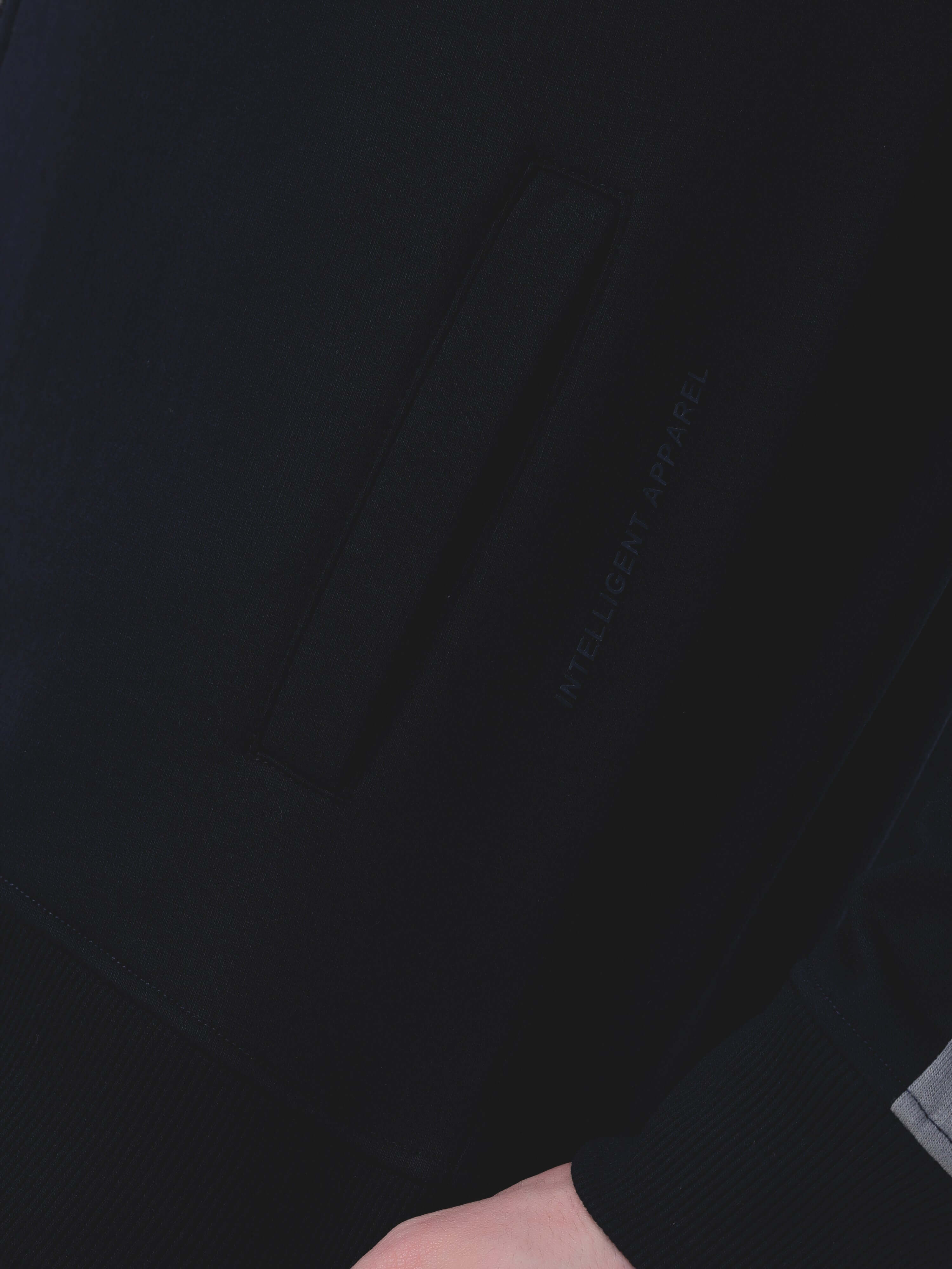 Close-up of Turms Intelligent Cord Set pocket, showcasing stylish design and premium fabric of black jacket.