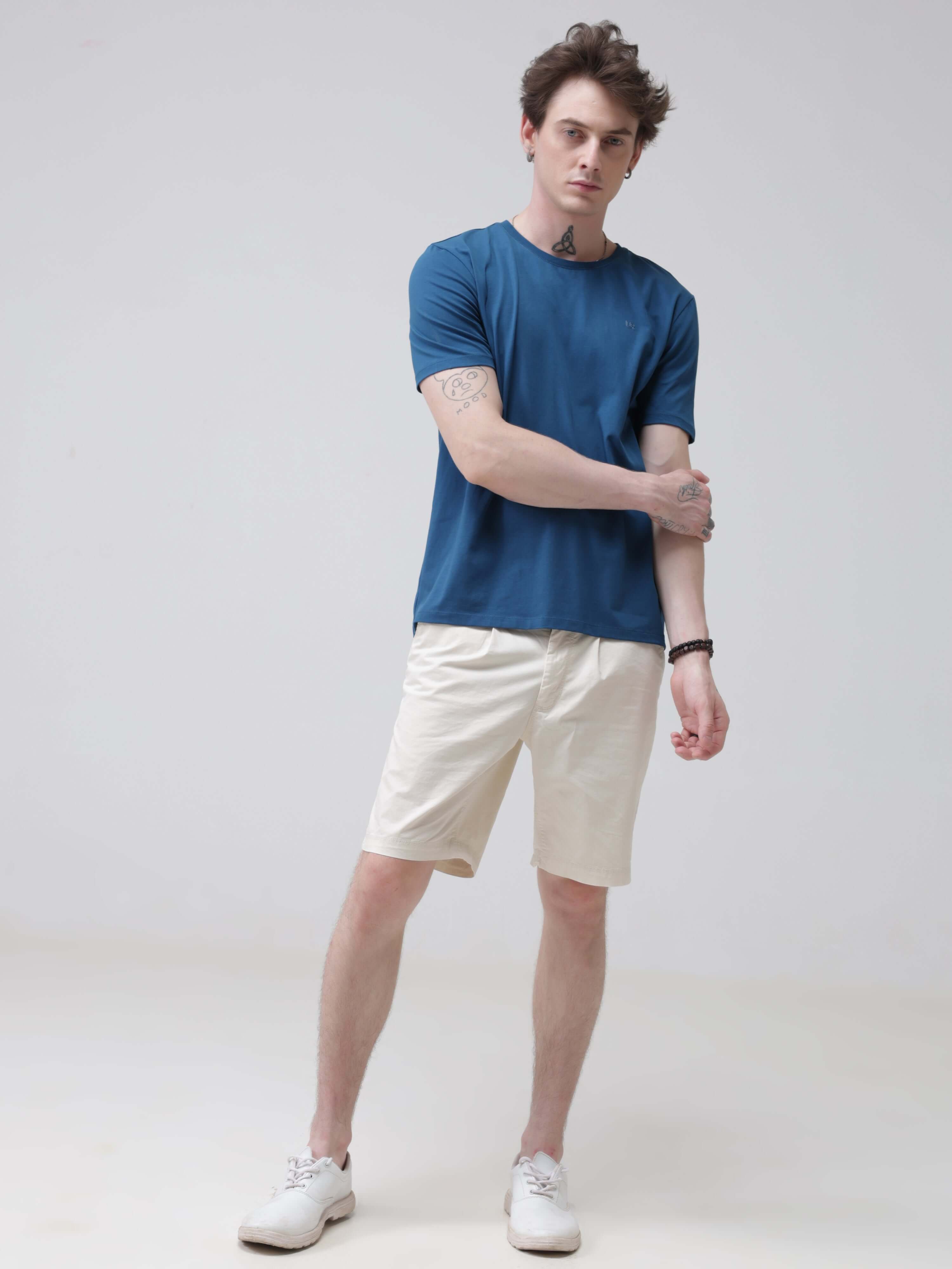 Stylish man wearing Sea Blue round neck Turms T-shirt and beige shorts, showcasing trendy and stain-proof tshirts for men.