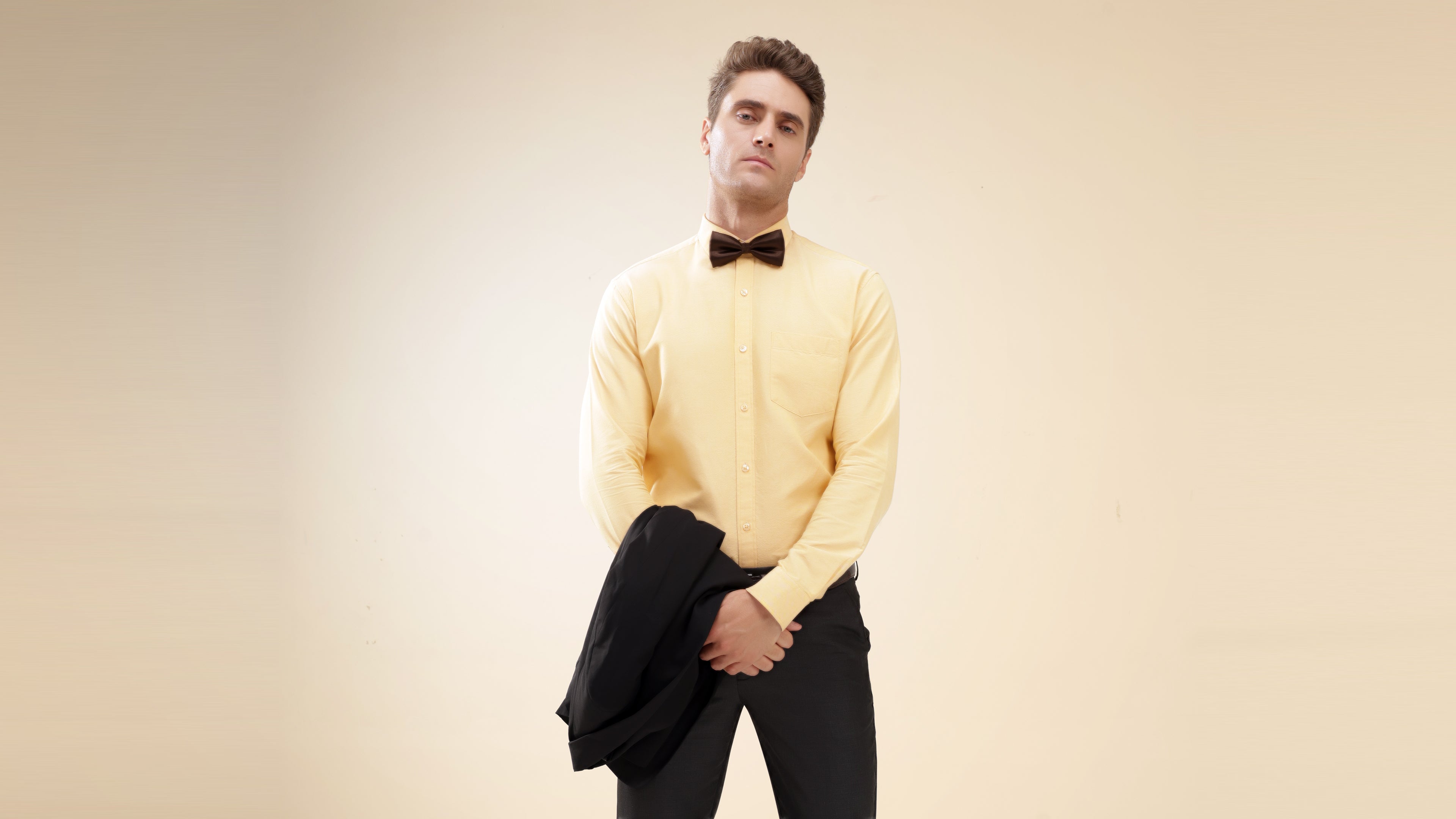 Stylish man in yellow shirt and bow tie, showcasing Turms intelligent apparel in modern menswear fashion.