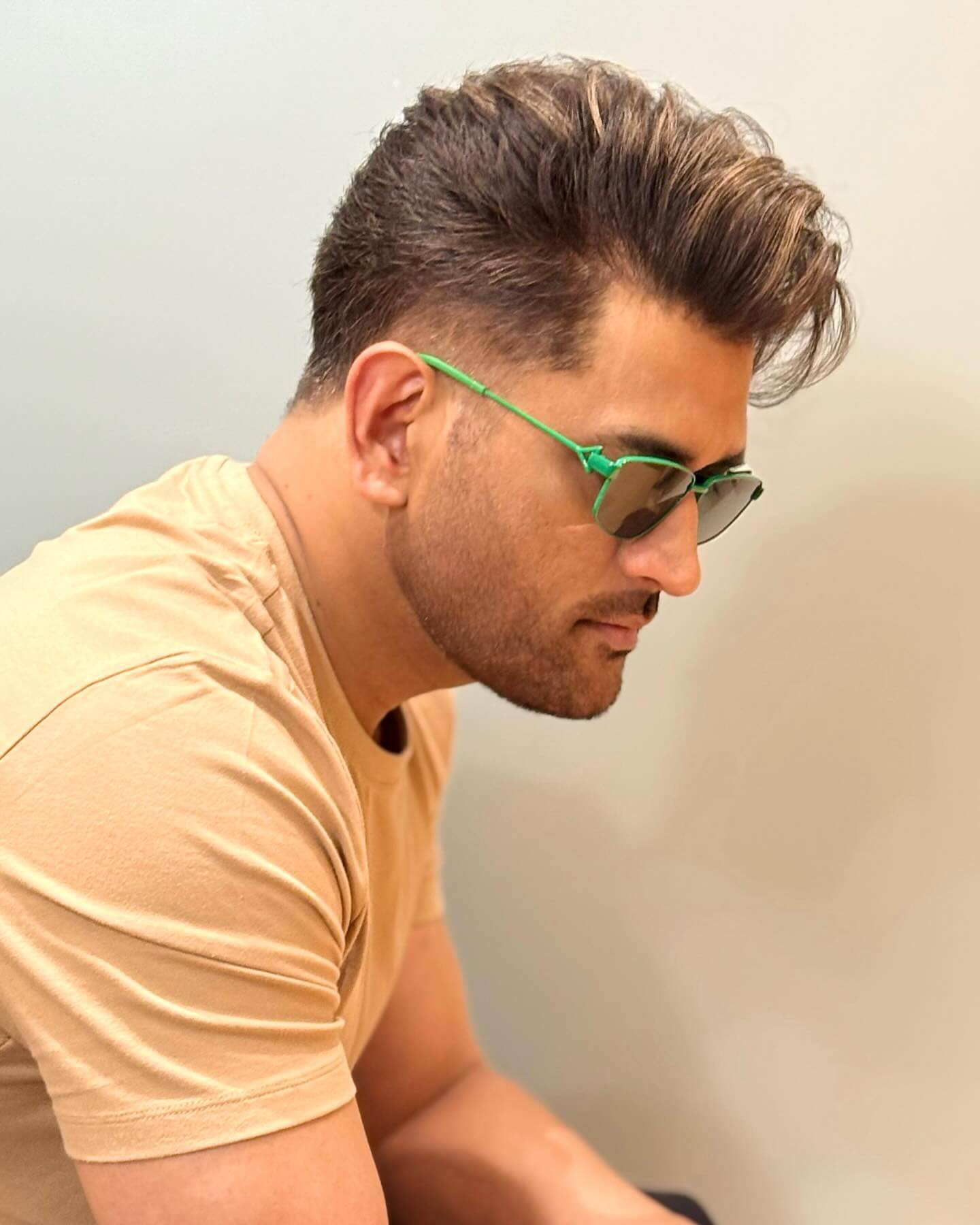 MS Dhoni in smart casual wear, showcasing intelligent apparel with stylish green sunglasses.