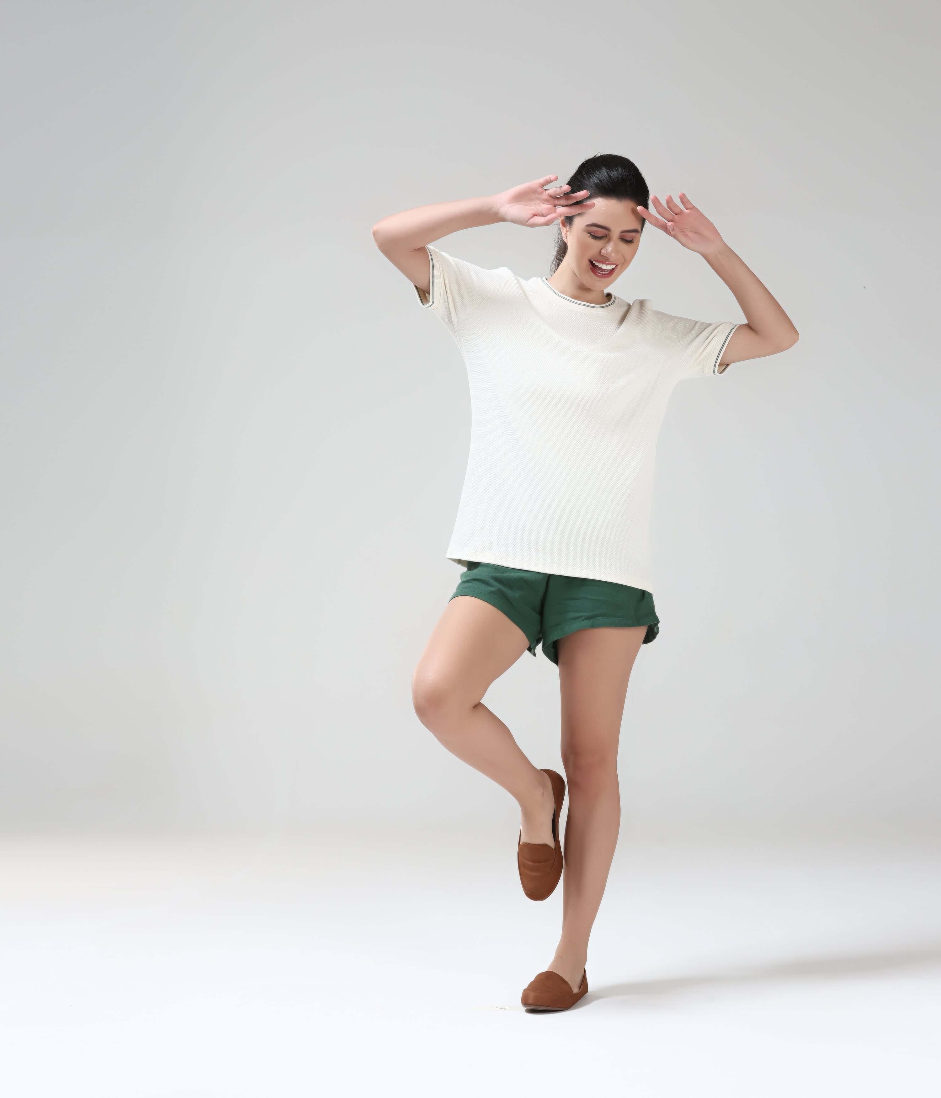 Woman wearing Pearl Off-White COOLTECH T-Shirt with green shorts, featuring honeycomb fabric. NEW COLOUR, anti-odour, and intelligent apparel by Turms.