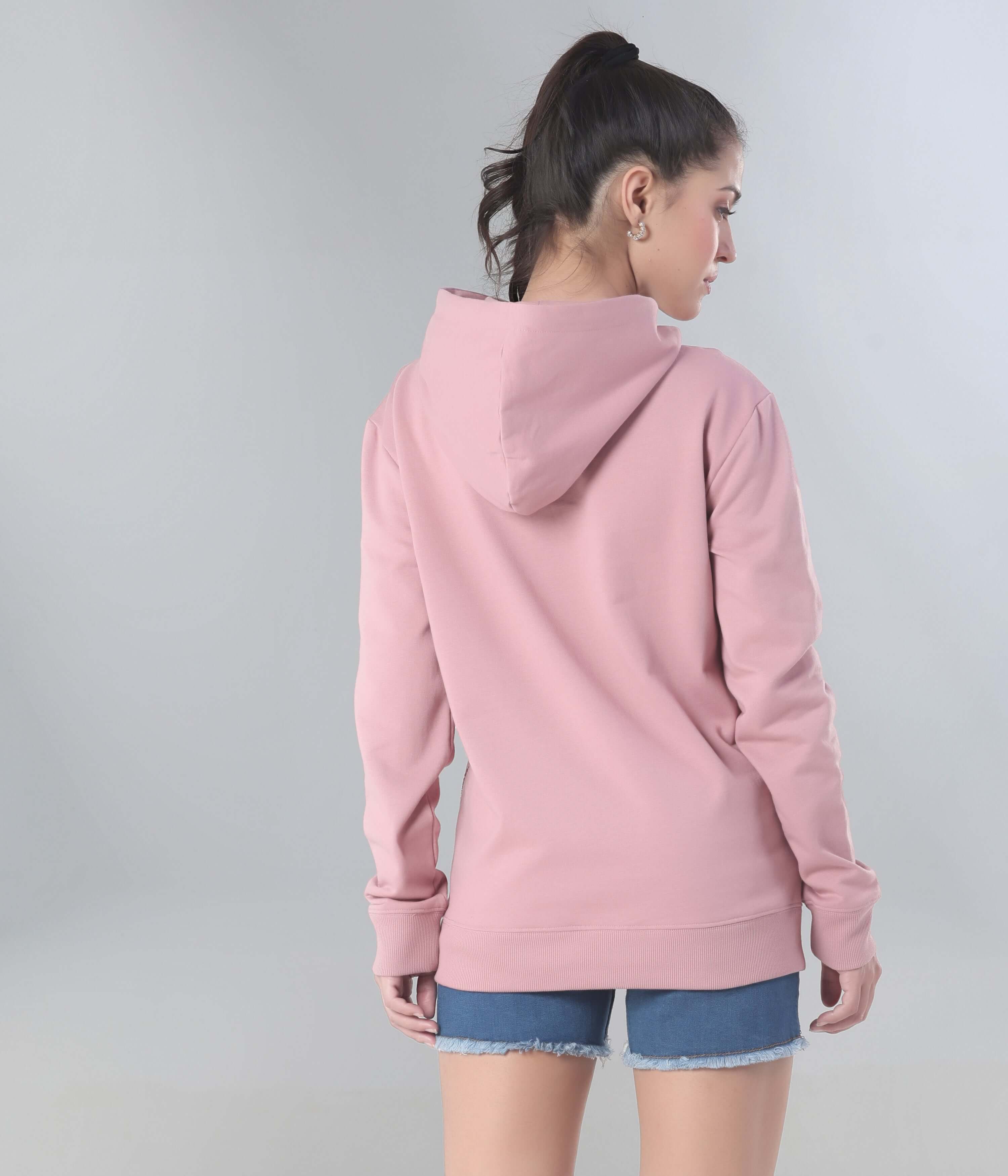 Woman wearing a pink hooded sweatshirt from the back, showcasing stylish design and comfortable fit, perfect for travel wear.