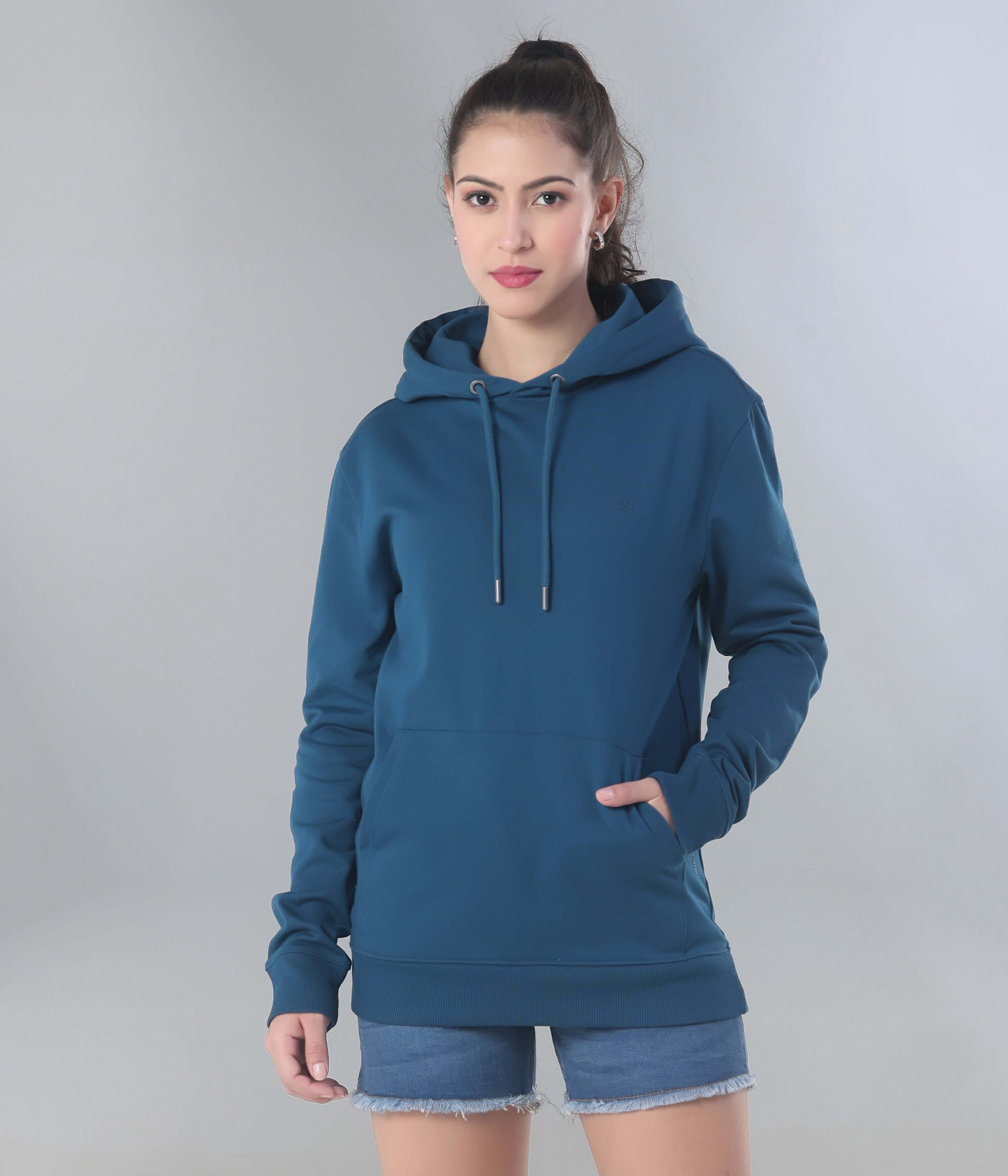 Stylish woman in a blue hooded sweatshirt, showcasing the best women's hoodie for travel wear, featuring anti-stain and water-resistant technology.