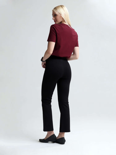 Woman wearing Turms cranberry round-neck T-shirt and black pants, showcasing stylish stain-proof and odor-resistant casual wear for everyday use.