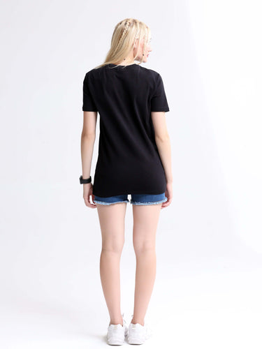 Woman wearing a black stain-proof and odor-resistant round-neck Turms T-shirt, paired with blue denim shorts and white sneakers.