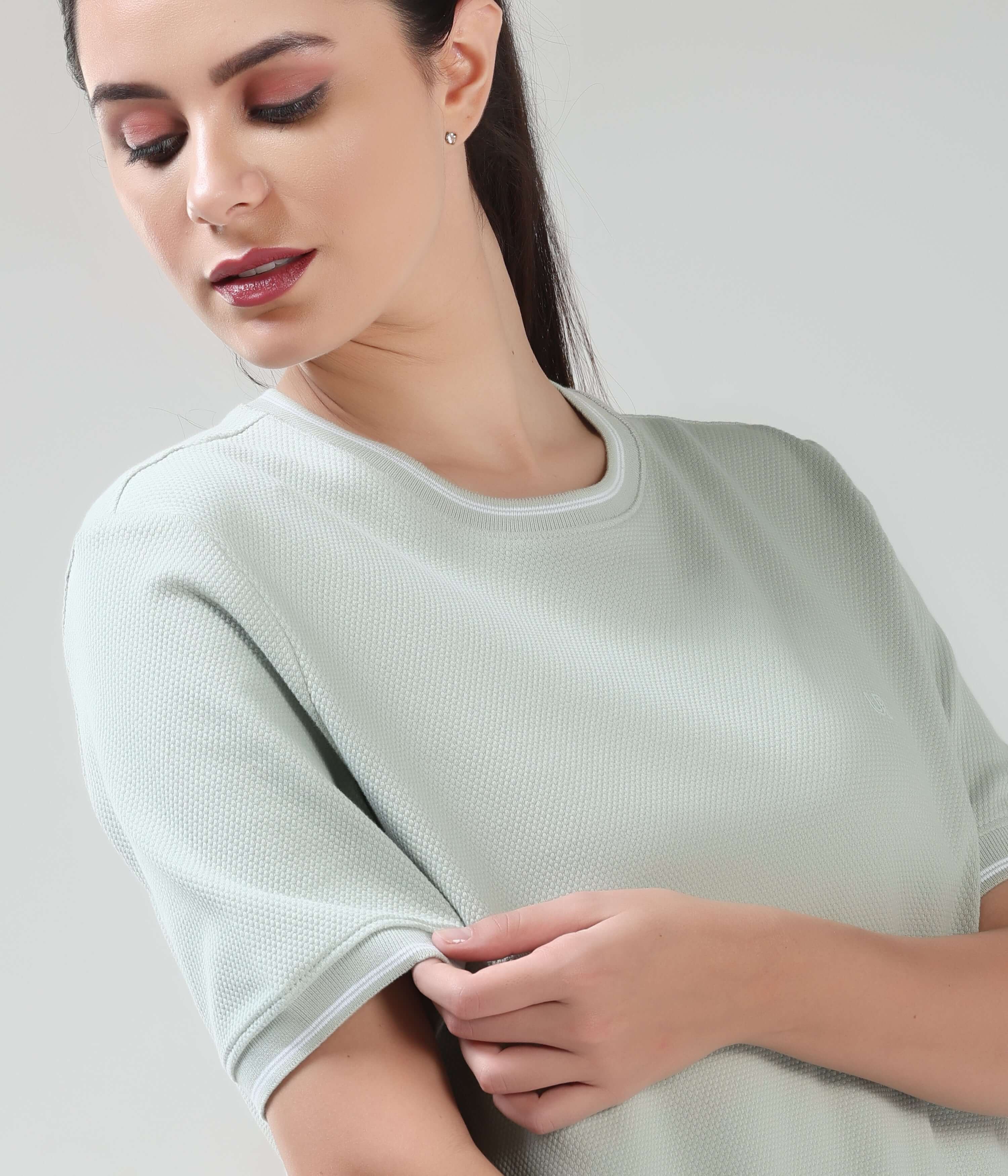 Woman wearing Serene Light Green COOLTECH T-shirt by TURMS, featuring honey comb fabric and anti-odour intelligent apparel technology.