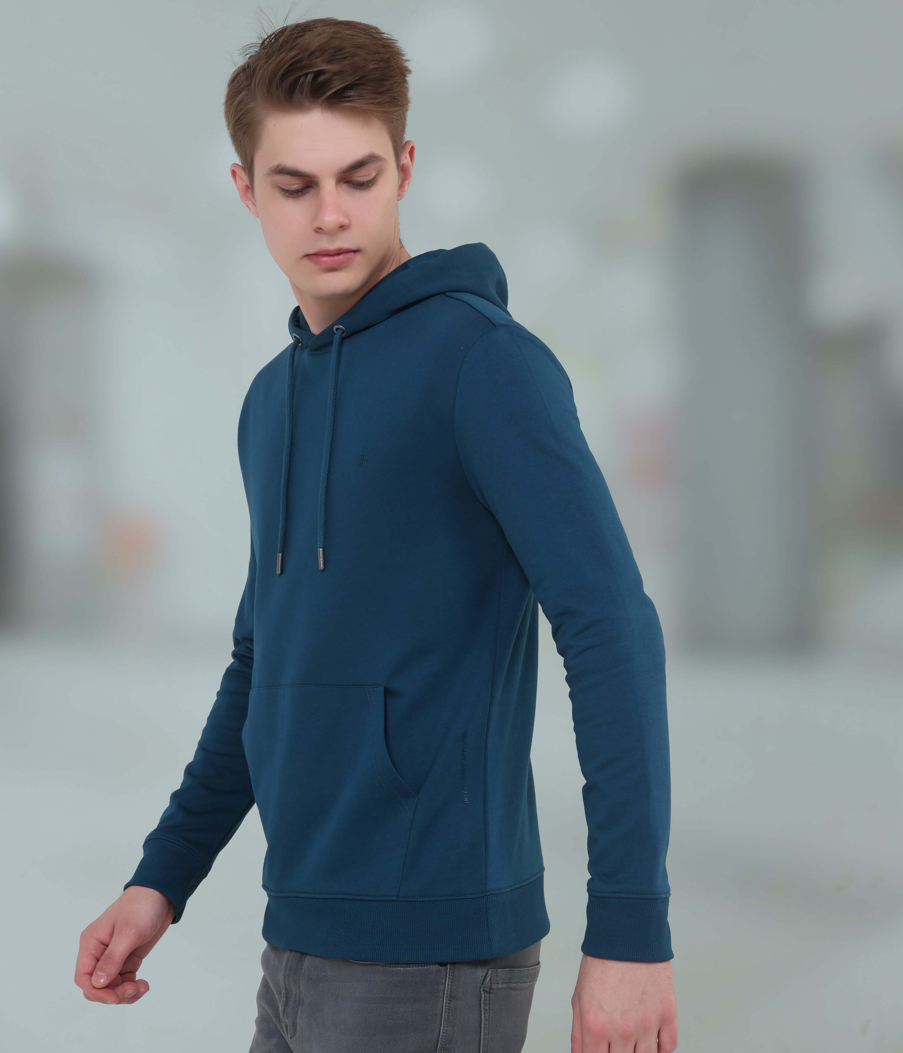 Young man wearing a blue hooded sweatshirt, showcasing comfort and style, ideal for waterproof and stain-proof menswear.