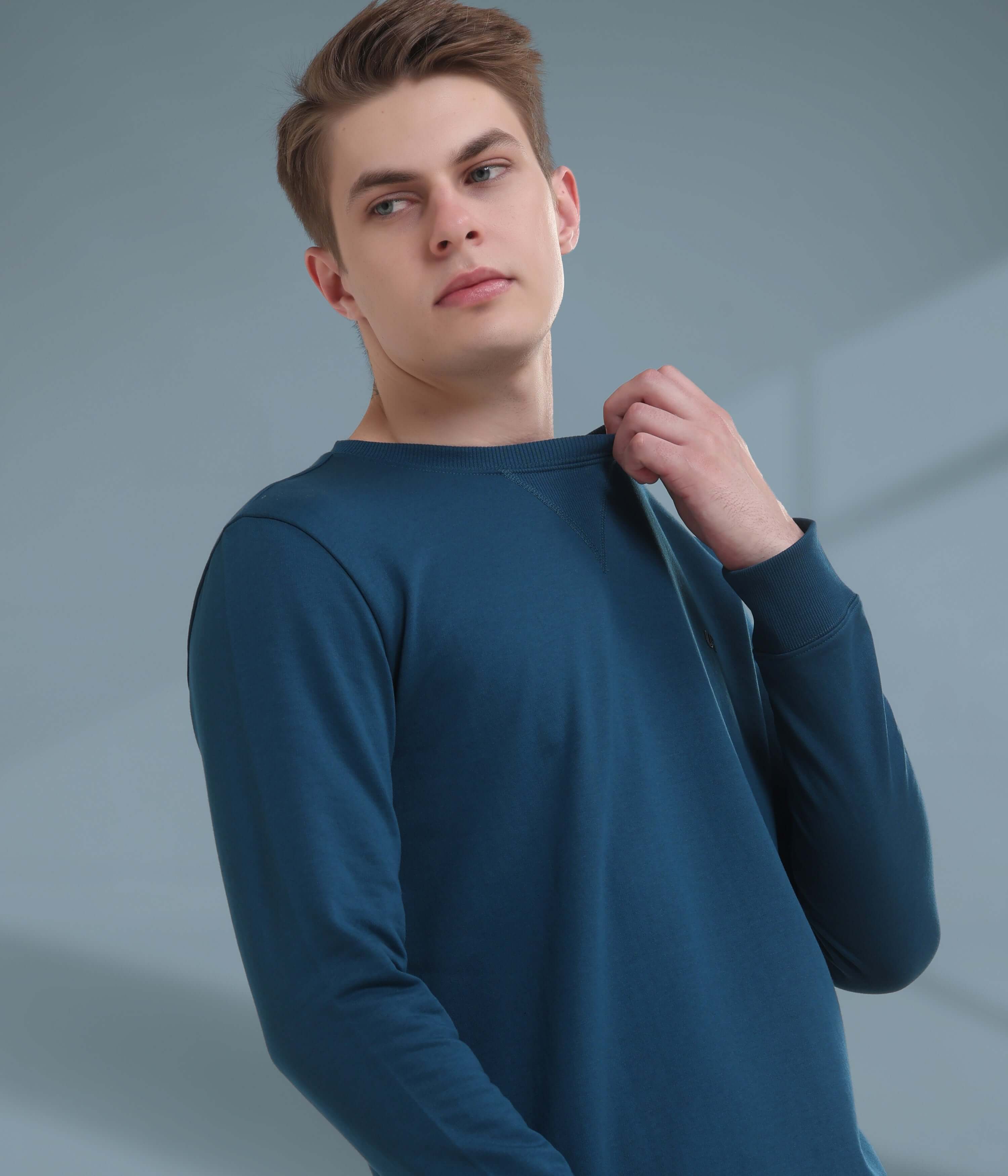 Young man wearing a stylish blue sweatshirt, showcasing comfort and modern design for everyday wear.