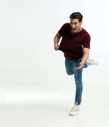 Man wearing a cranberry round-neck Turms T-shirt and jeans, demonstrating stain-proof and odor-resistant features, showcasing intelligent menswear.