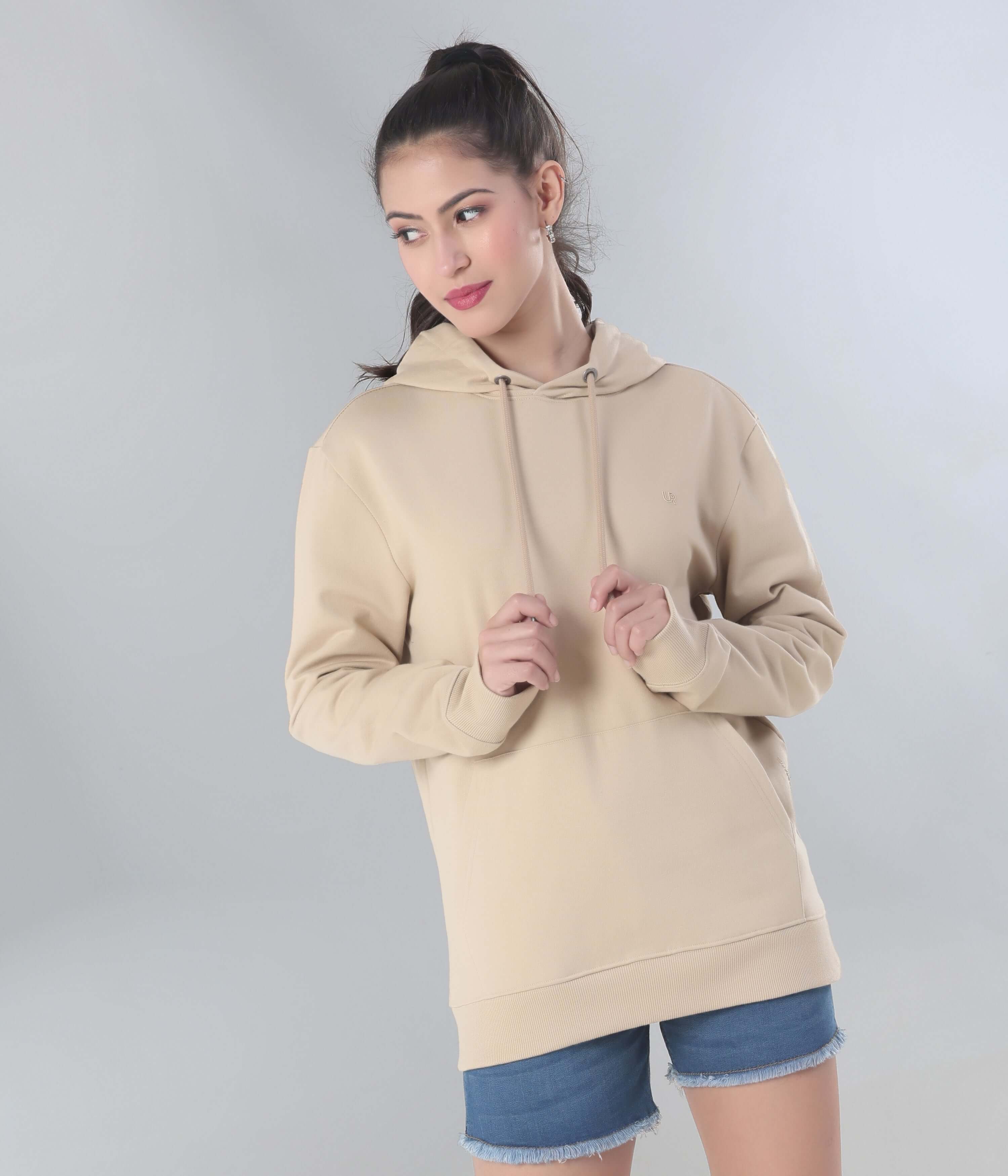 female model wearing a beige hooded sweatshirt, showcasing style and comfort in casual travel wear.