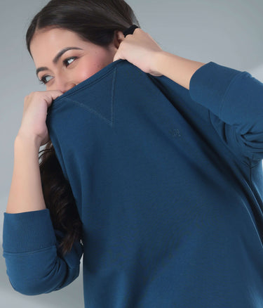 Woman wearing a blue Turms Intelligent Sweatshirt, showcasing its soft fabric and stylish V-notch neckline for travel wear.