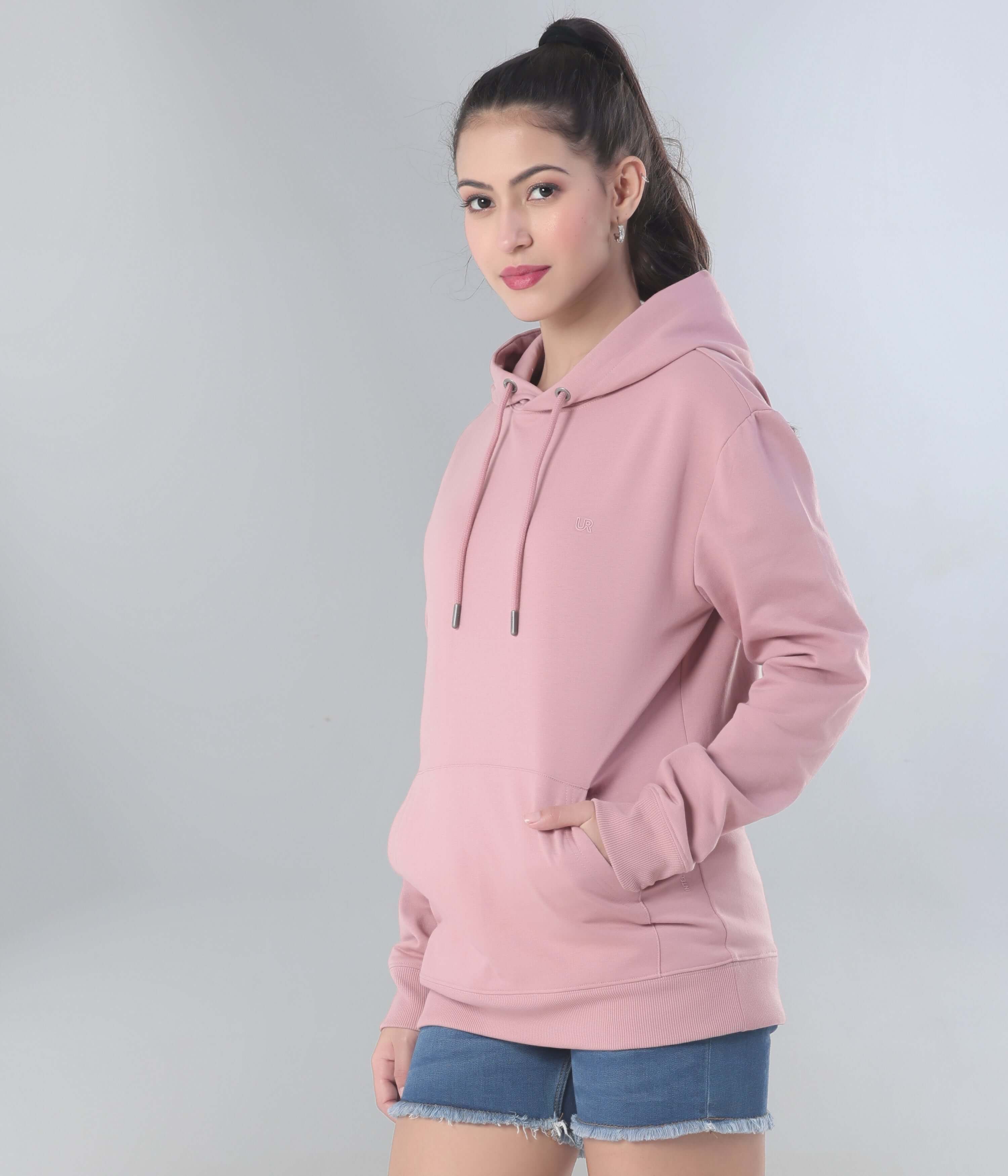 Stylish woman wearing a pink hooded sweatshirt, showcasing comfort and versatility for everyday wear.