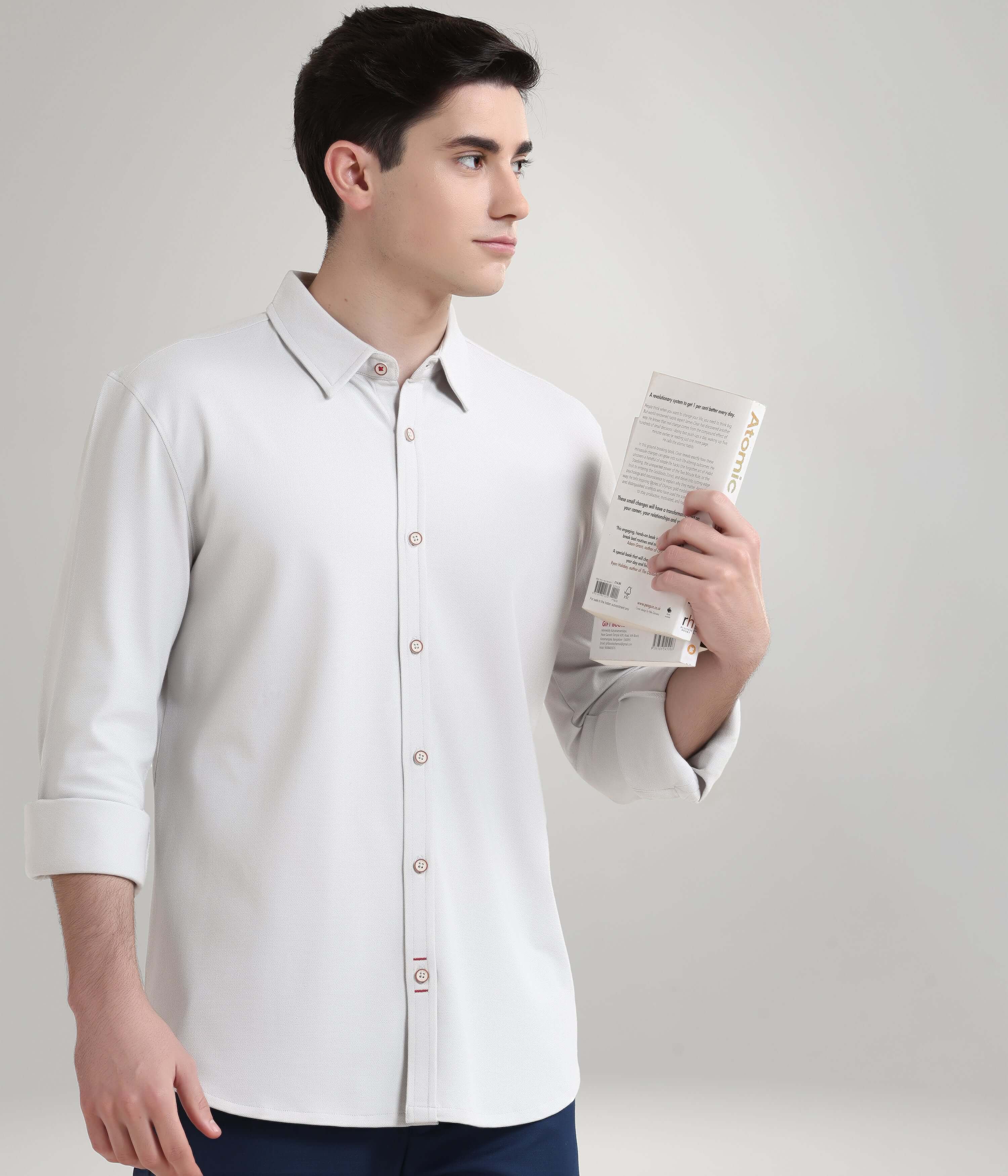 Man wearing an Ashen Grey knitted stretchable shirt holding a book, showcasing premium menswear with anti-stain and anti-odor features.