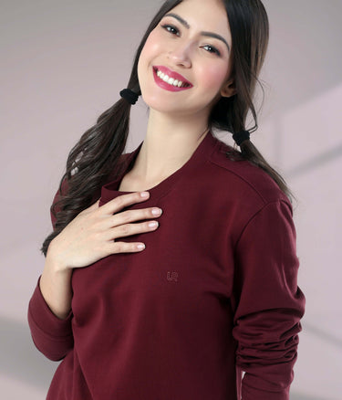 Woman smiling in a burgundy Turms Intelligent Sweatshirt, showcasing comfort and style for everyday wear.
