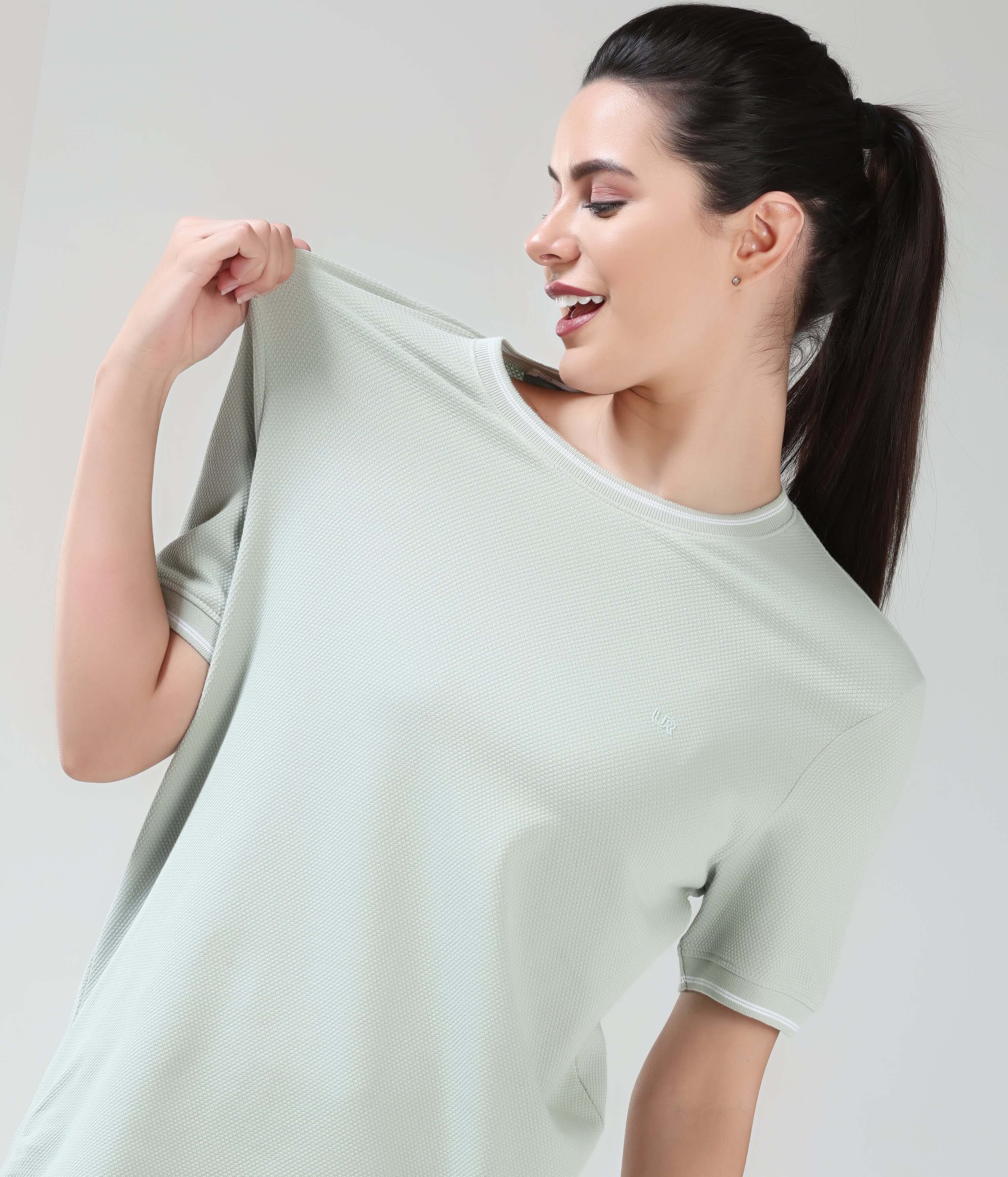 Woman wearing a Serene Light Green coolant round-neck Turms T-shirt with COOLTECH technology, showcasing tailored fit and honeycomb fabric, anti-odour.