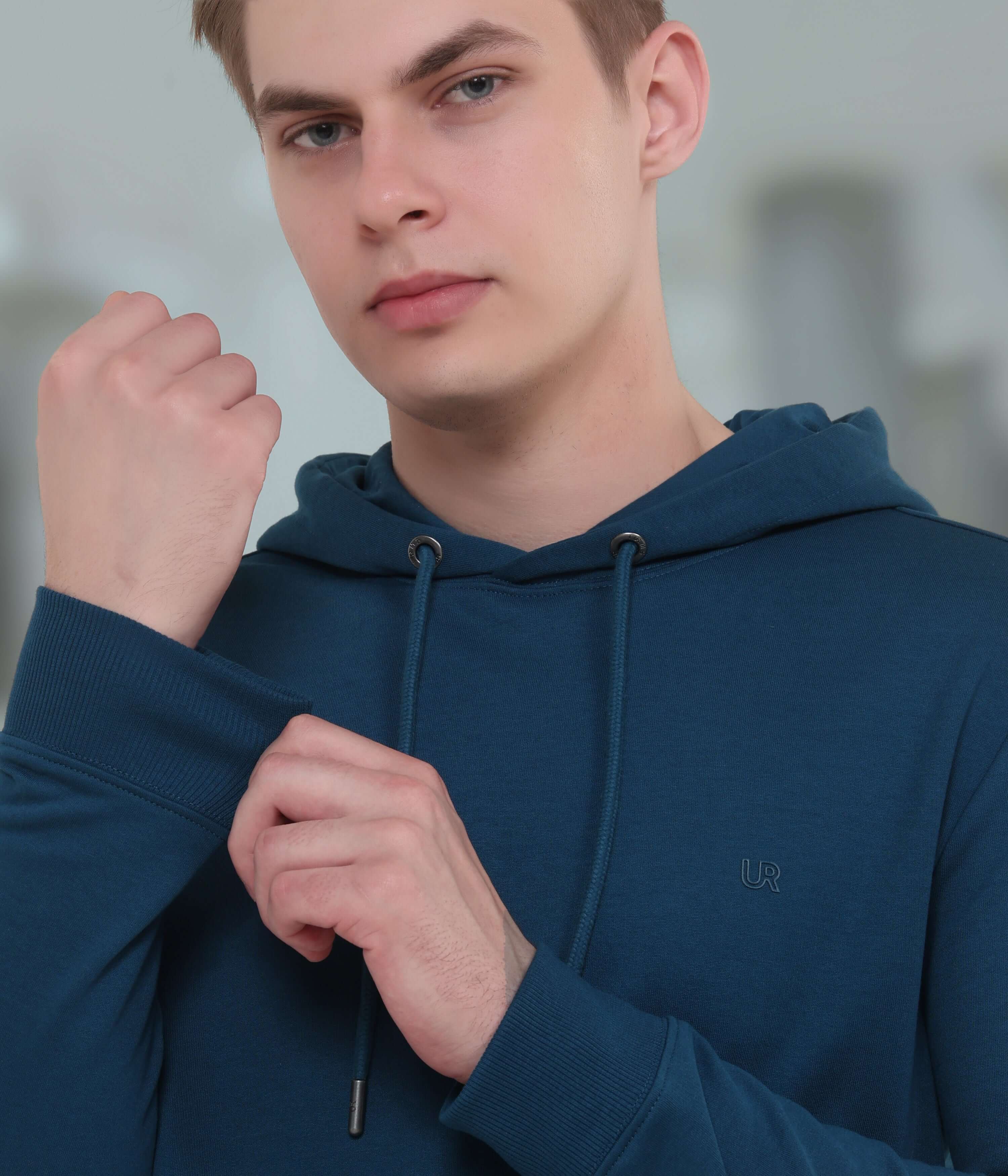 Young man in a blue hooded sweatshirt showcasing the soft, stylish, and waterproof fabric for fashionable everyday wear.