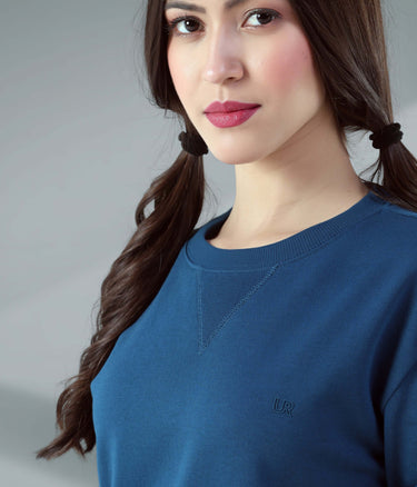 Woman wearing a blue sweatshirt featuring a V-notch neckline, demonstrating style and comfort in travel wear.