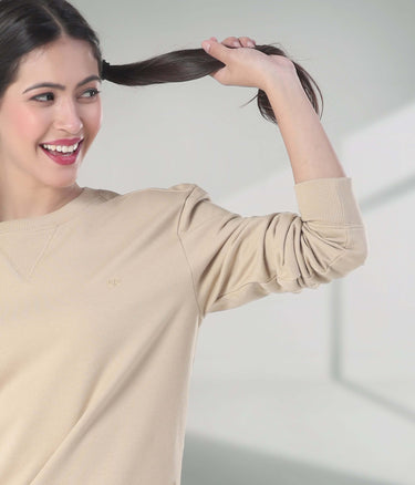 Model wearing a beige Turms Intelligent Sweatshirt, showcasing style and comfort in a playful pose.