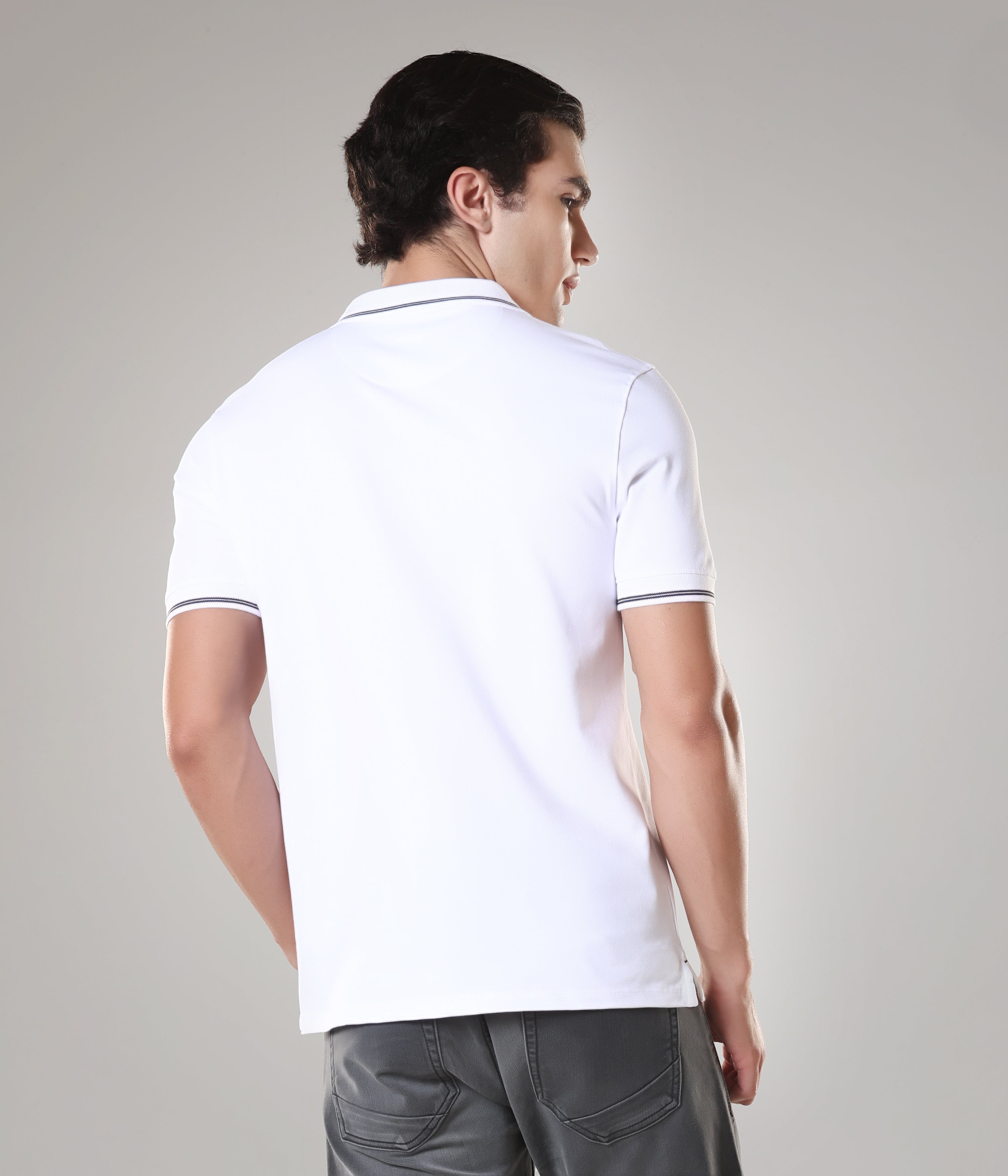 Man wearing a white Turms Polo T-shirt with tailored fit, showcasing anti-stain, anti-odour, and anti-microbial features, made with premium cotton and spandex.