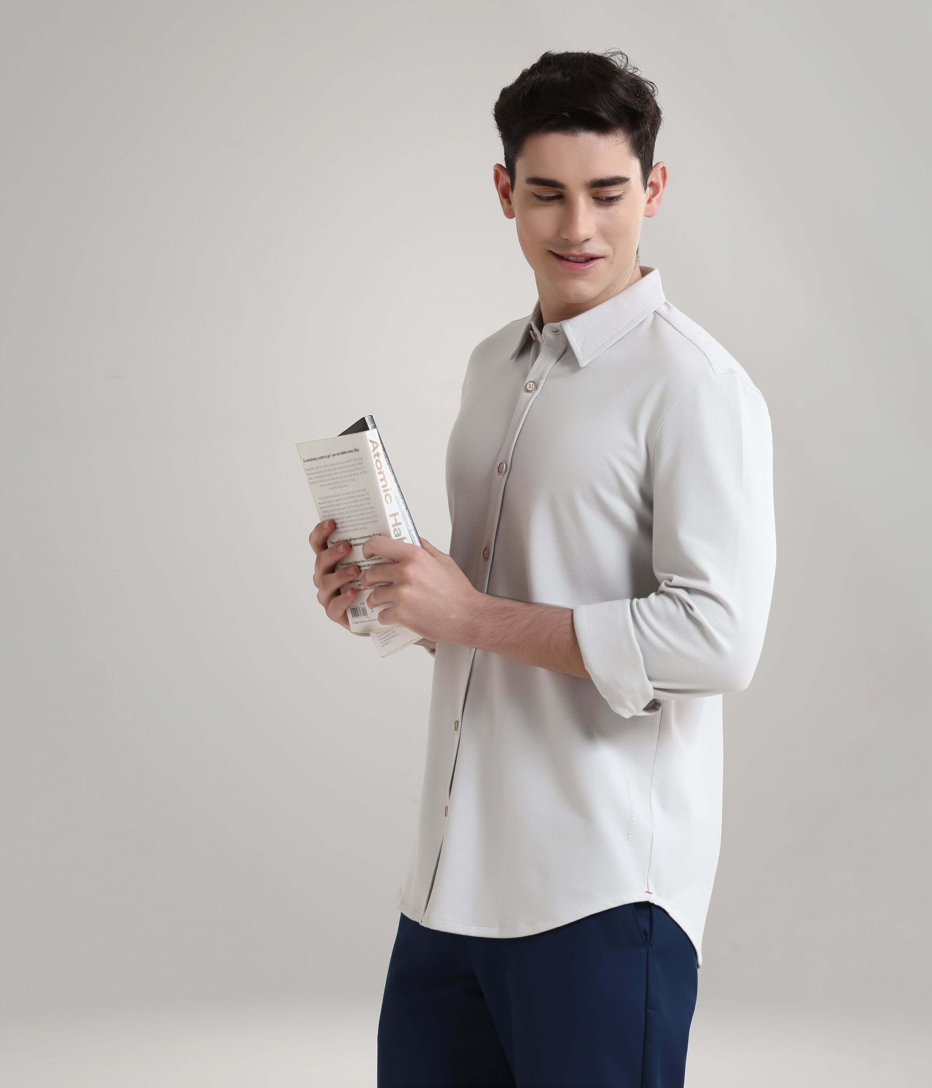 Man wearing Ashen Grey Knitted Turms Stretchable Shirt, premium menswear with anti-stain and anti-odour features, holding a book.