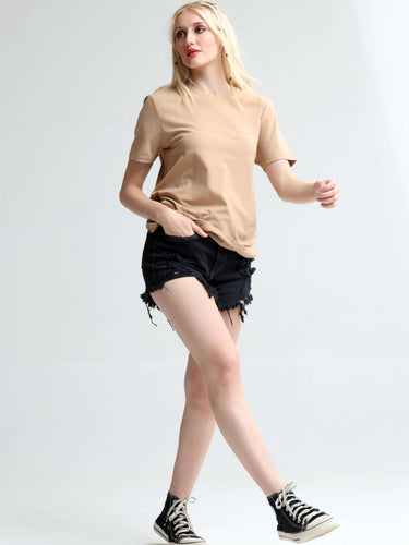 Woman wearing camel round-neck Turms T-shirt and black shorts, showcasing stylish and stain-proof casual wear for women.