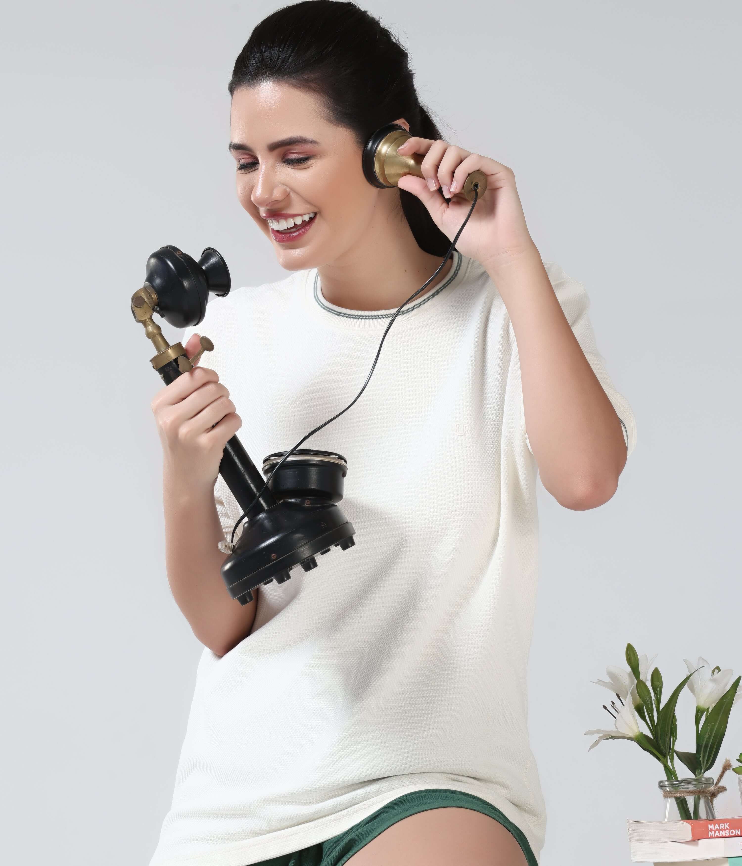 Woman wearing Pearl Off White COOLTECH TSHIRT by Turms, using an antique phone, showcasing new colour and honey comb fabric with anti-odour feature.