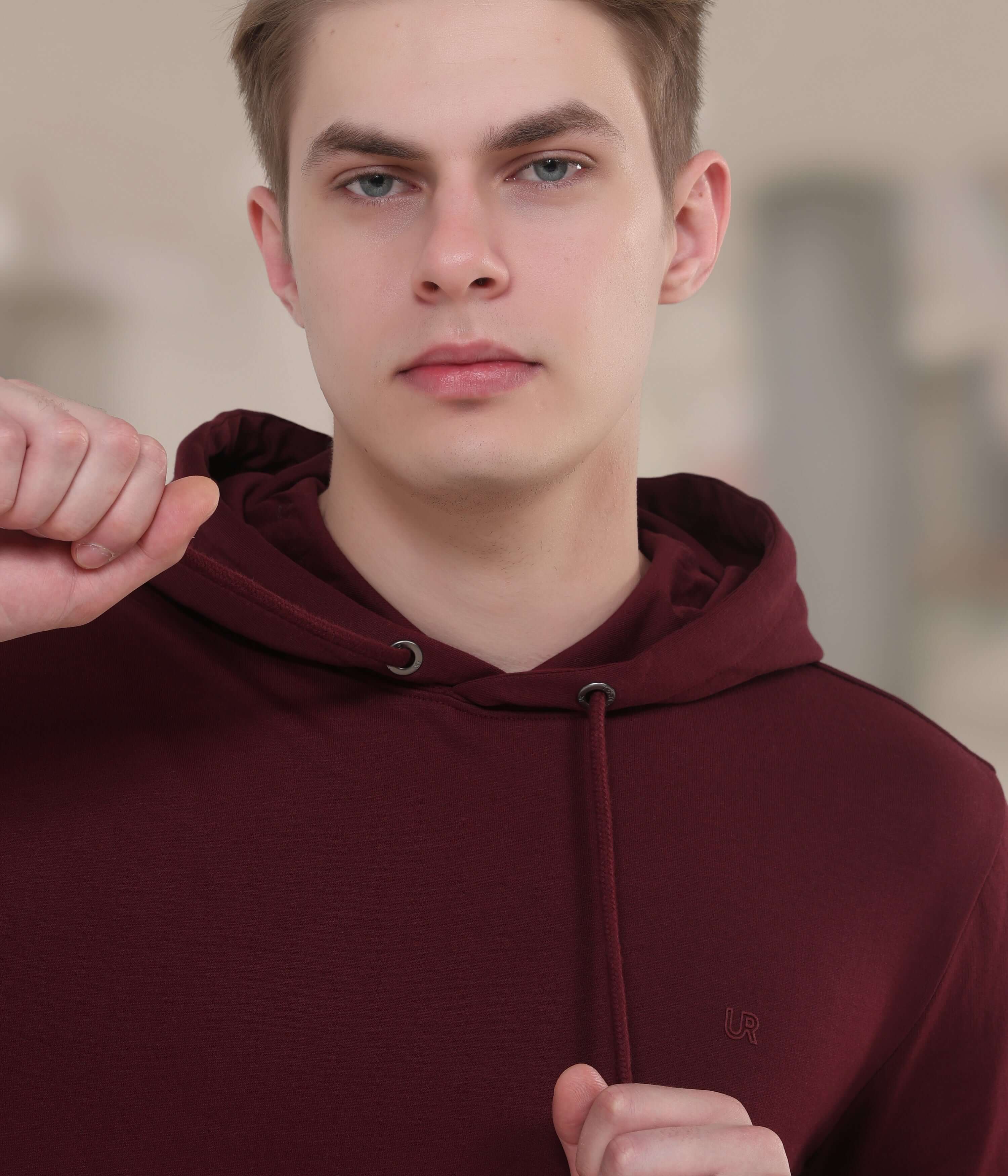 Stylish man in a burgundy hooded sweatshirt, showcasing comfort and innovative waterproof features for everyday wear.