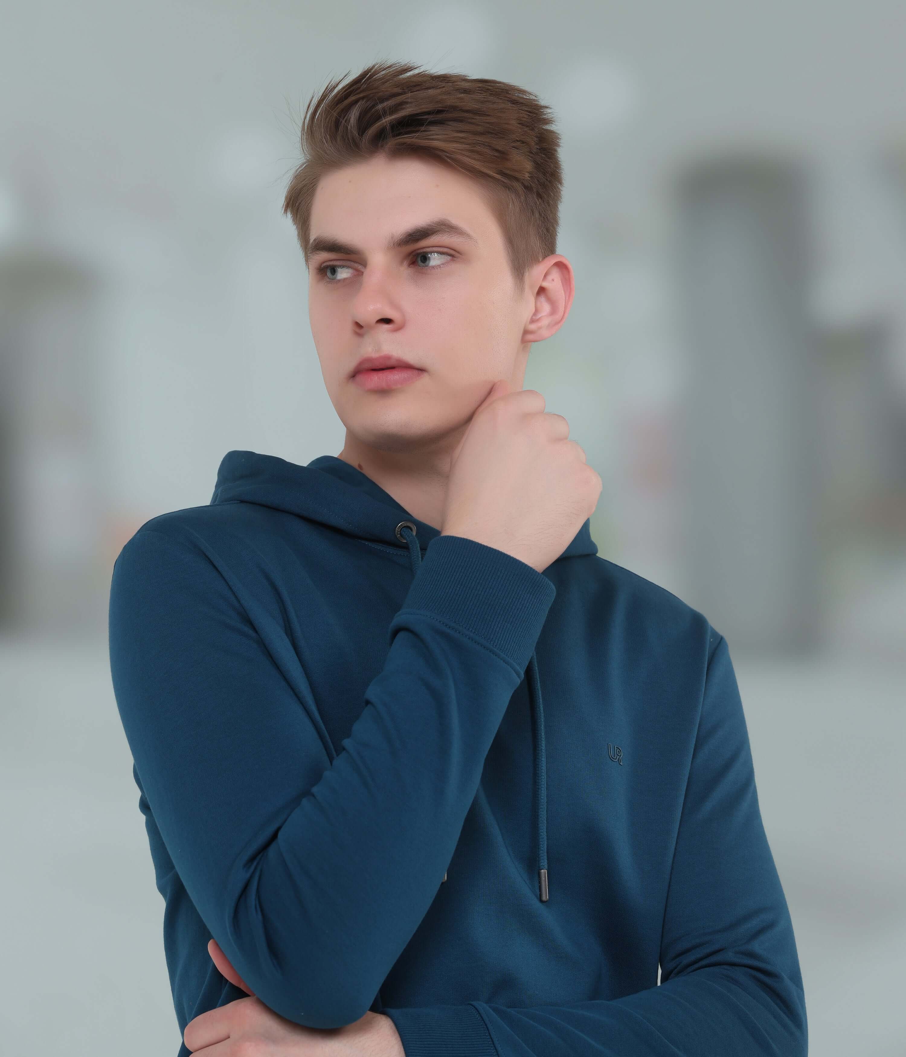 Young man wearing a blue hooded sweatshirt, showcasing style and comfort in modern menswear.