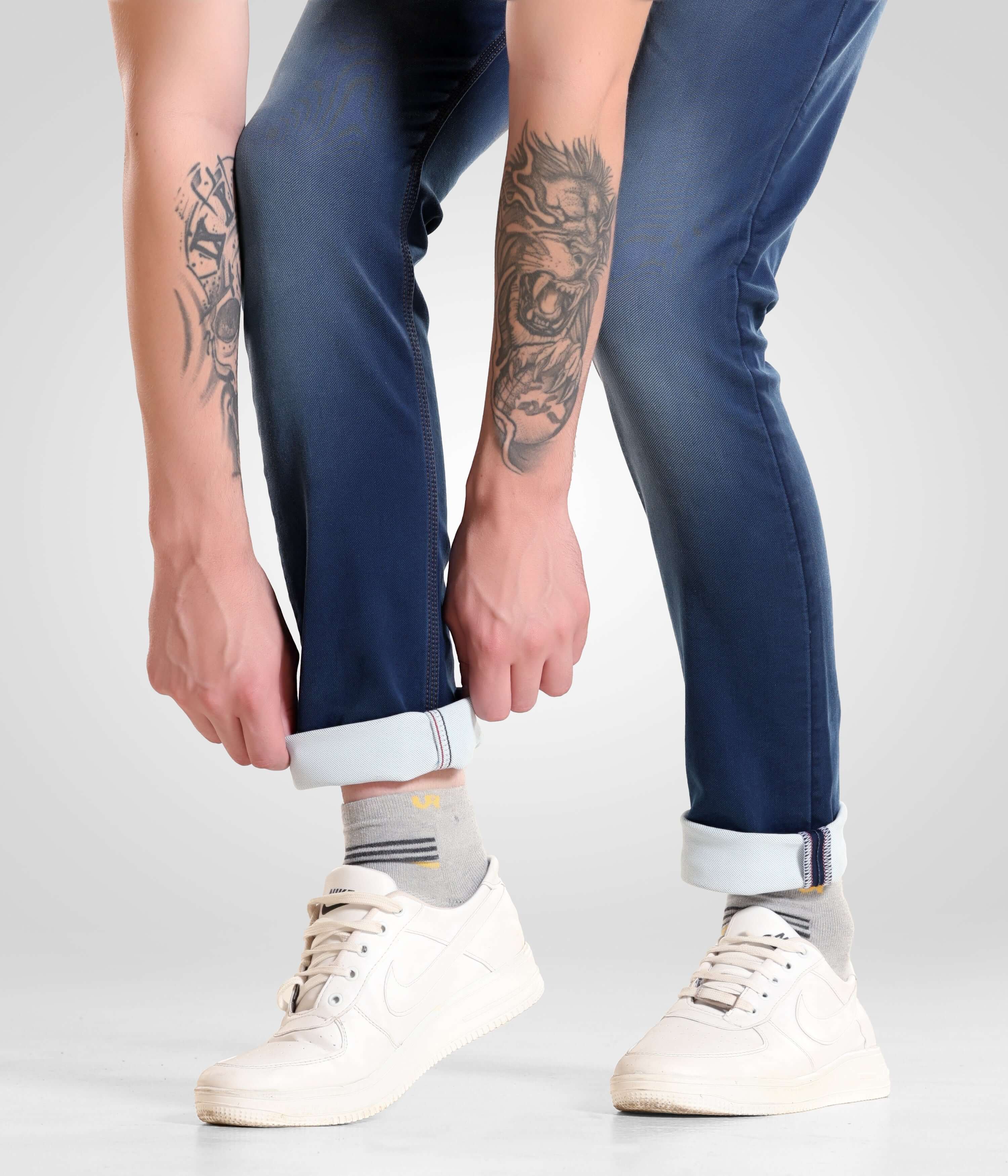 Man wearing Noir Blue high-performance denim pants from Turms Intelligent Apparel, menswear best brand, adjusting cuffs above white sneakers