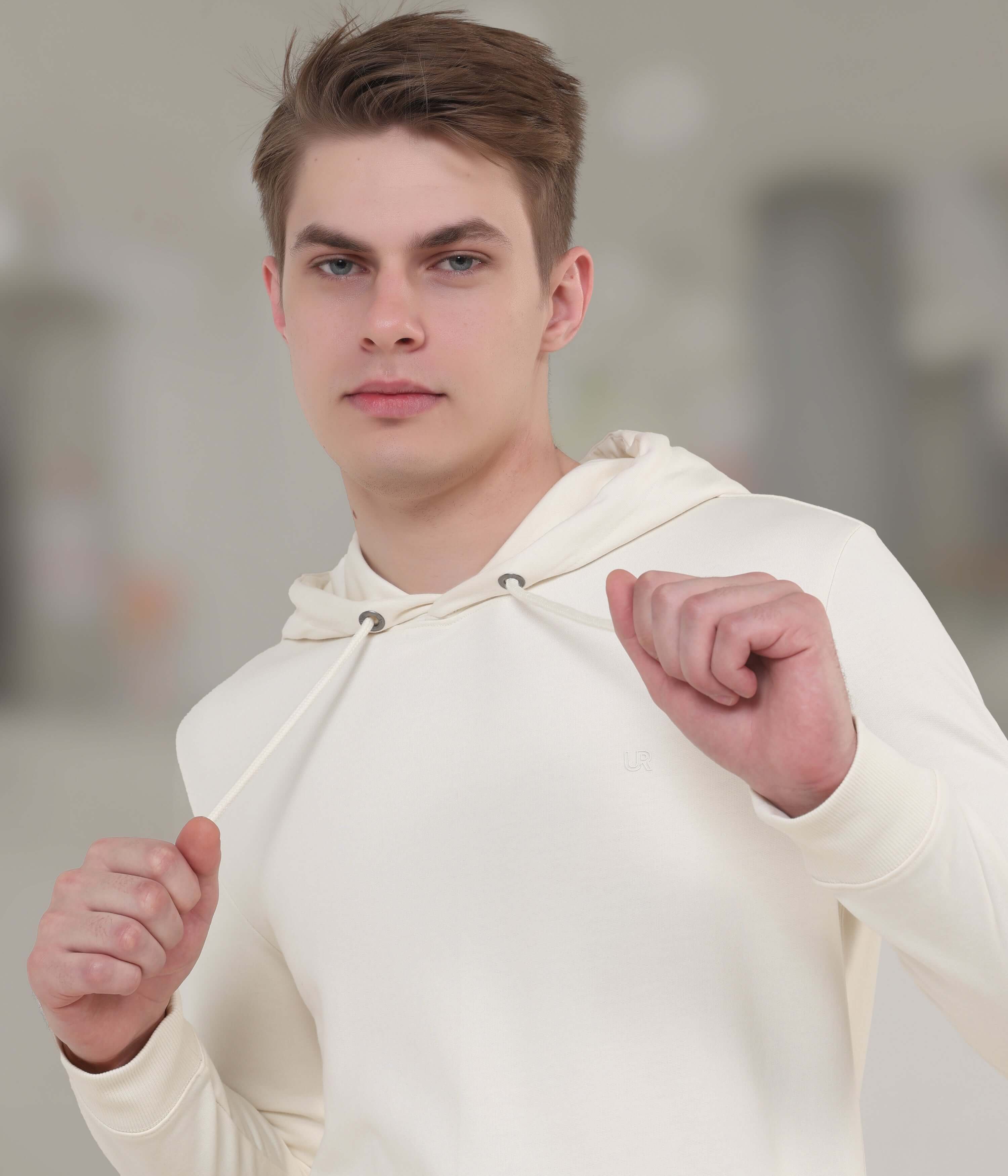 Young man wearing a cream-colored waterproof hoodie, showcasing style and comfort in everyday wear.