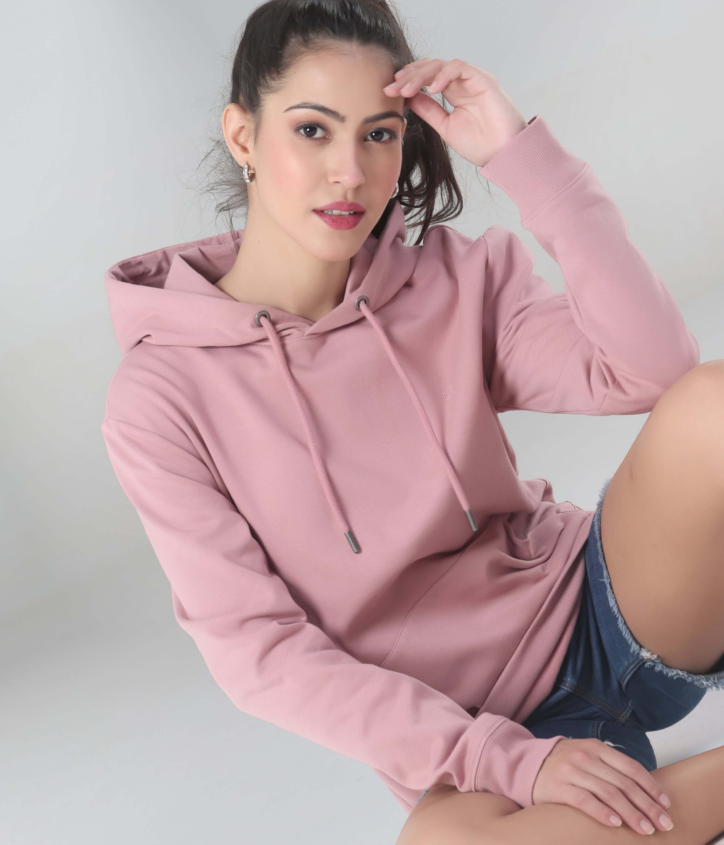 Woman wearing a pink hooded sweatshirt, showcasing style and comfort in premium cotton-blend fabric. Best womens hoodie.