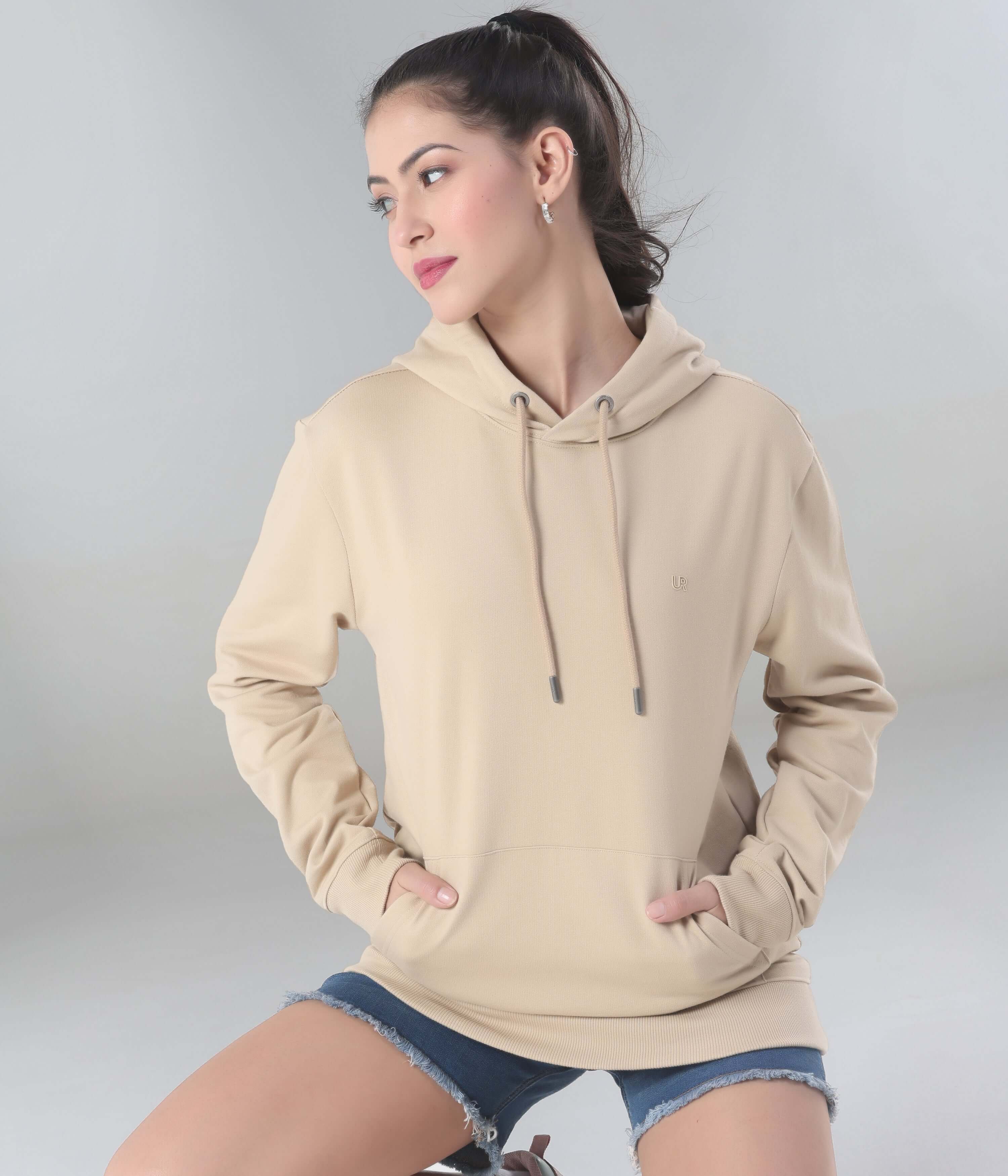 Woman wearing a beige Turms Intelligent Hooded Sweatshirt, showcasing style, comfort, and water-resistant features.