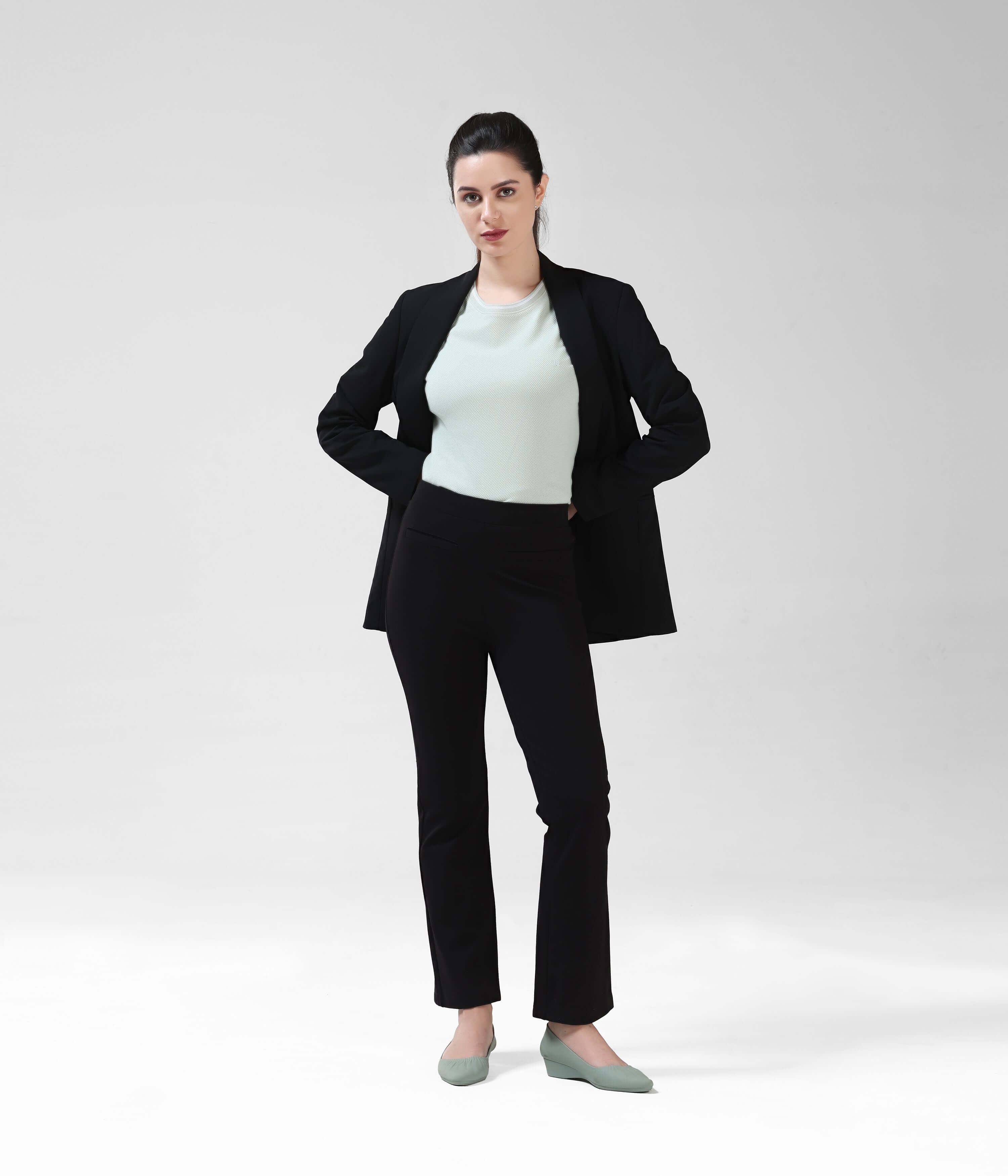 Woman wearing a Serene Light Green COOLTECH round-neck Turms T-shirt with tailored fit under black blazer, modeling anti-odour, intelligent apparel.