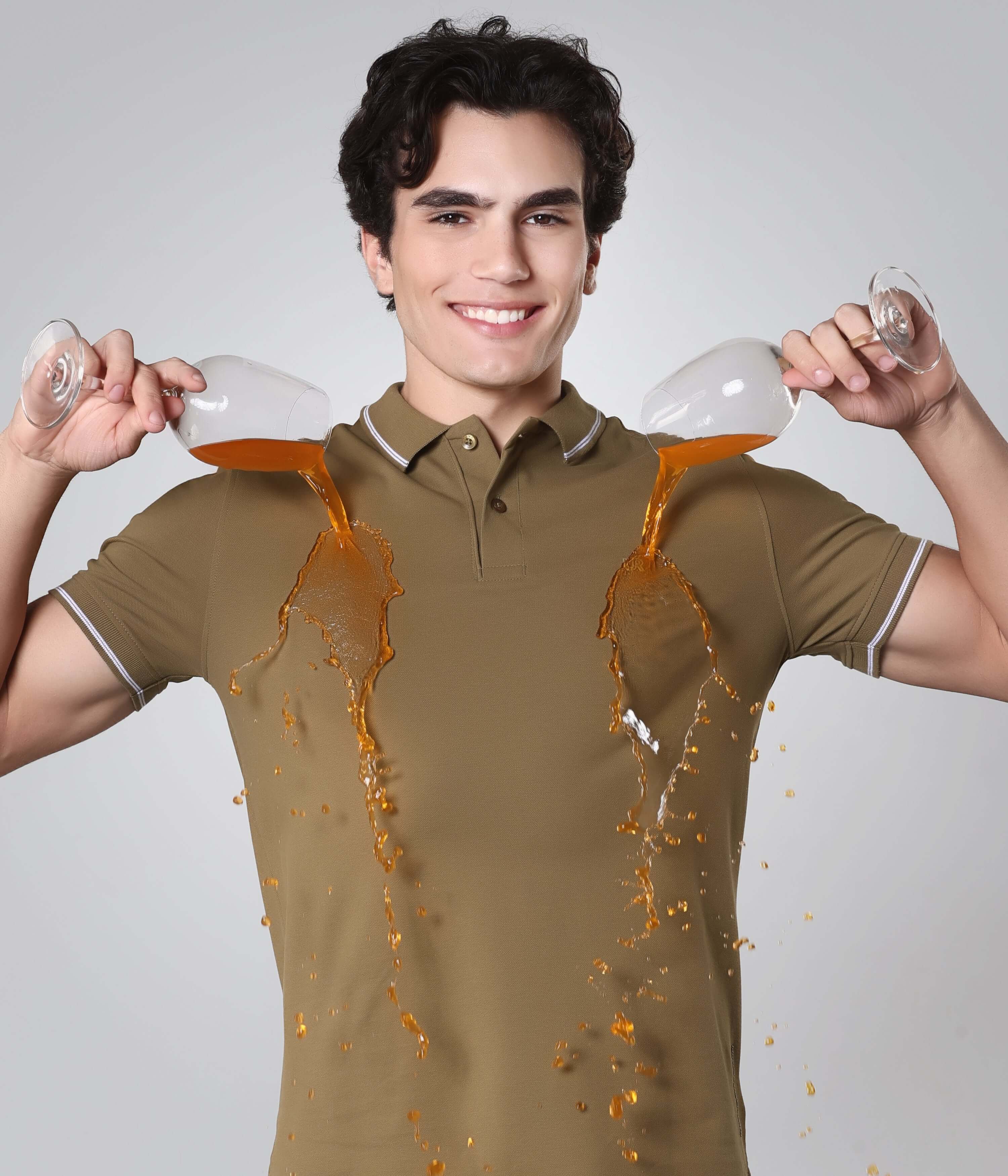 Man wearing Turms intelligent apparel Tranquil Green polo t-shirt demonstrating anti-stain feature with liquids spilling on it.