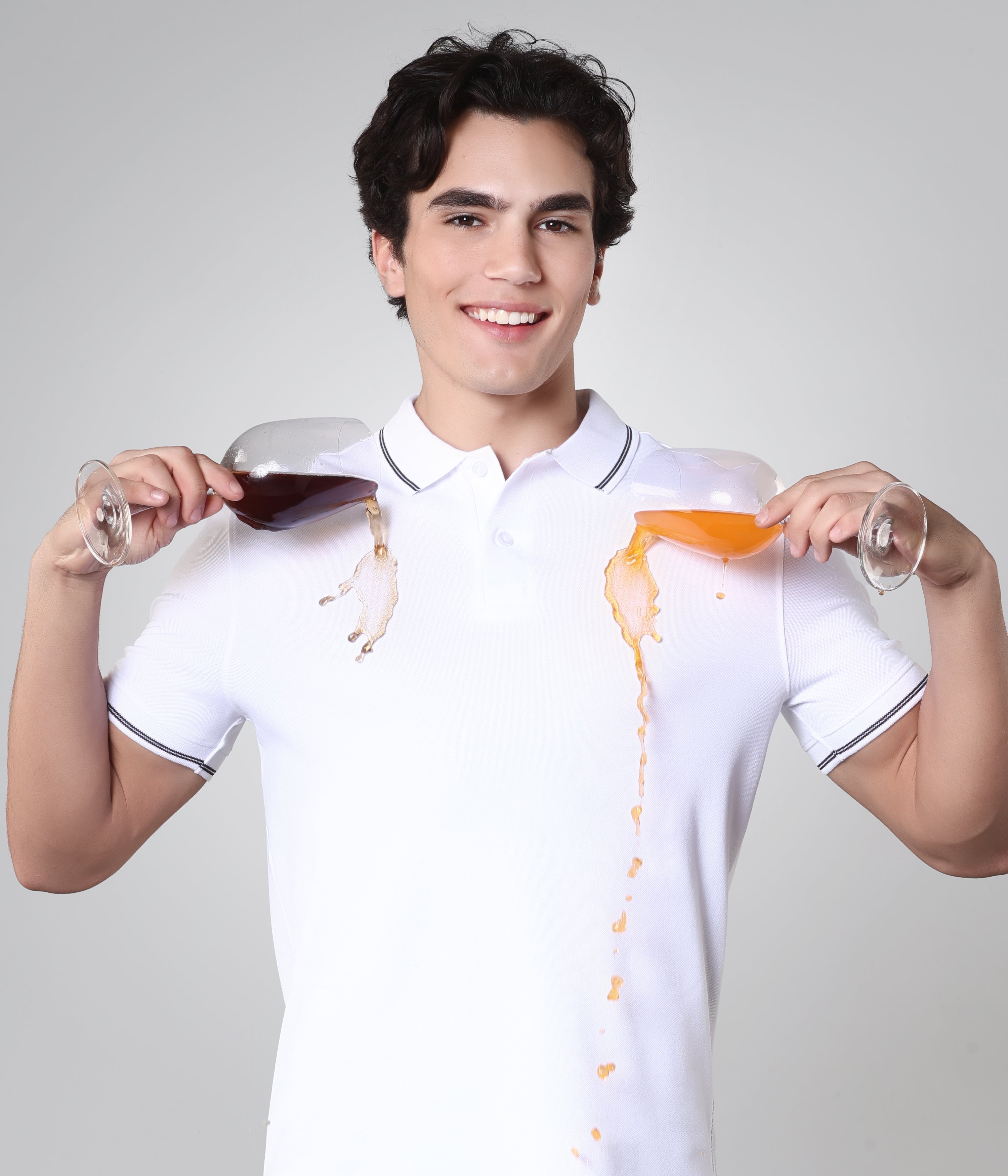 Man demonstrating stain-proof Turms Polo T-shirt by pouring liquids without causing stains.