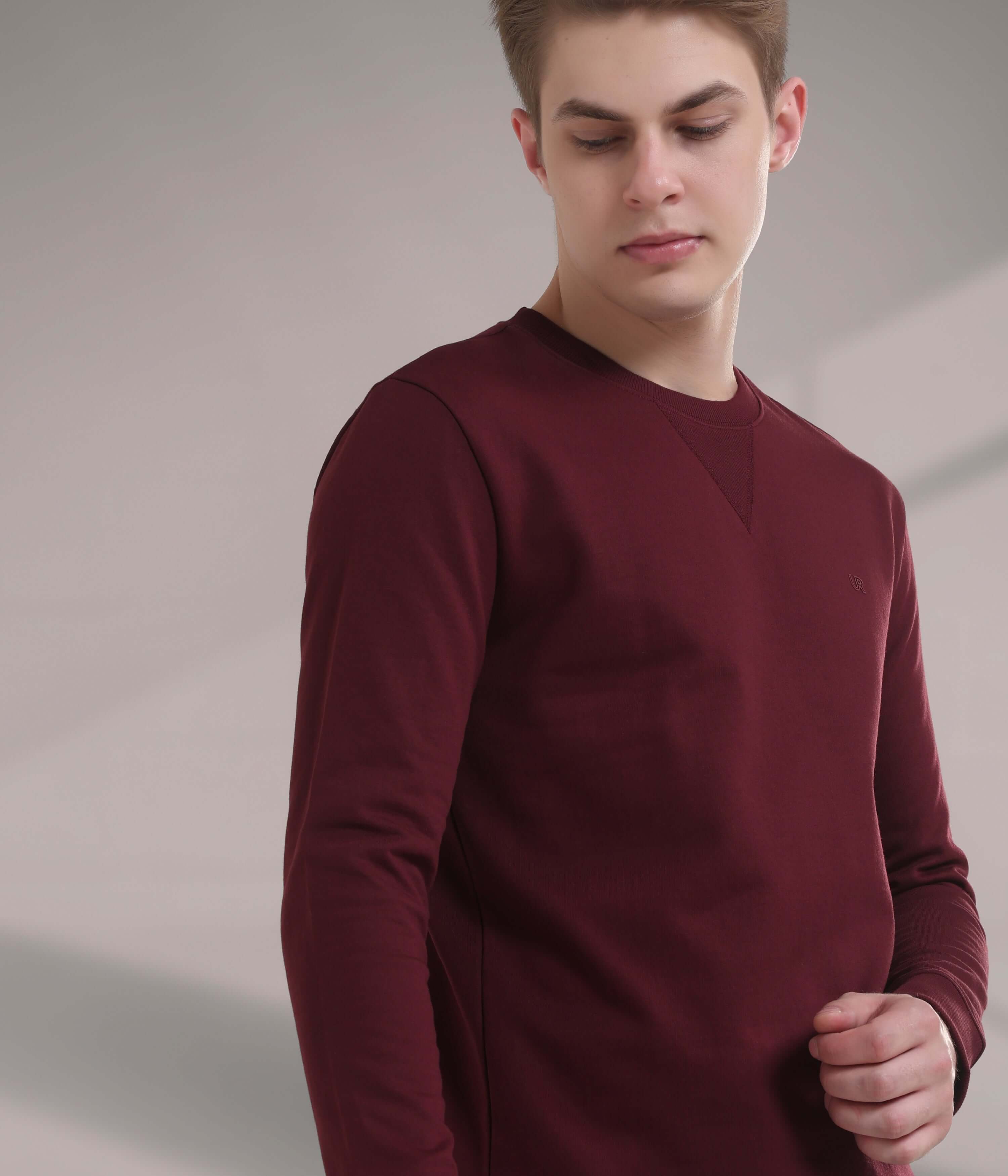 Young man wearing a burgundy Turms Intelligent Sweatshirt, showcasing style and comfort in menswear.