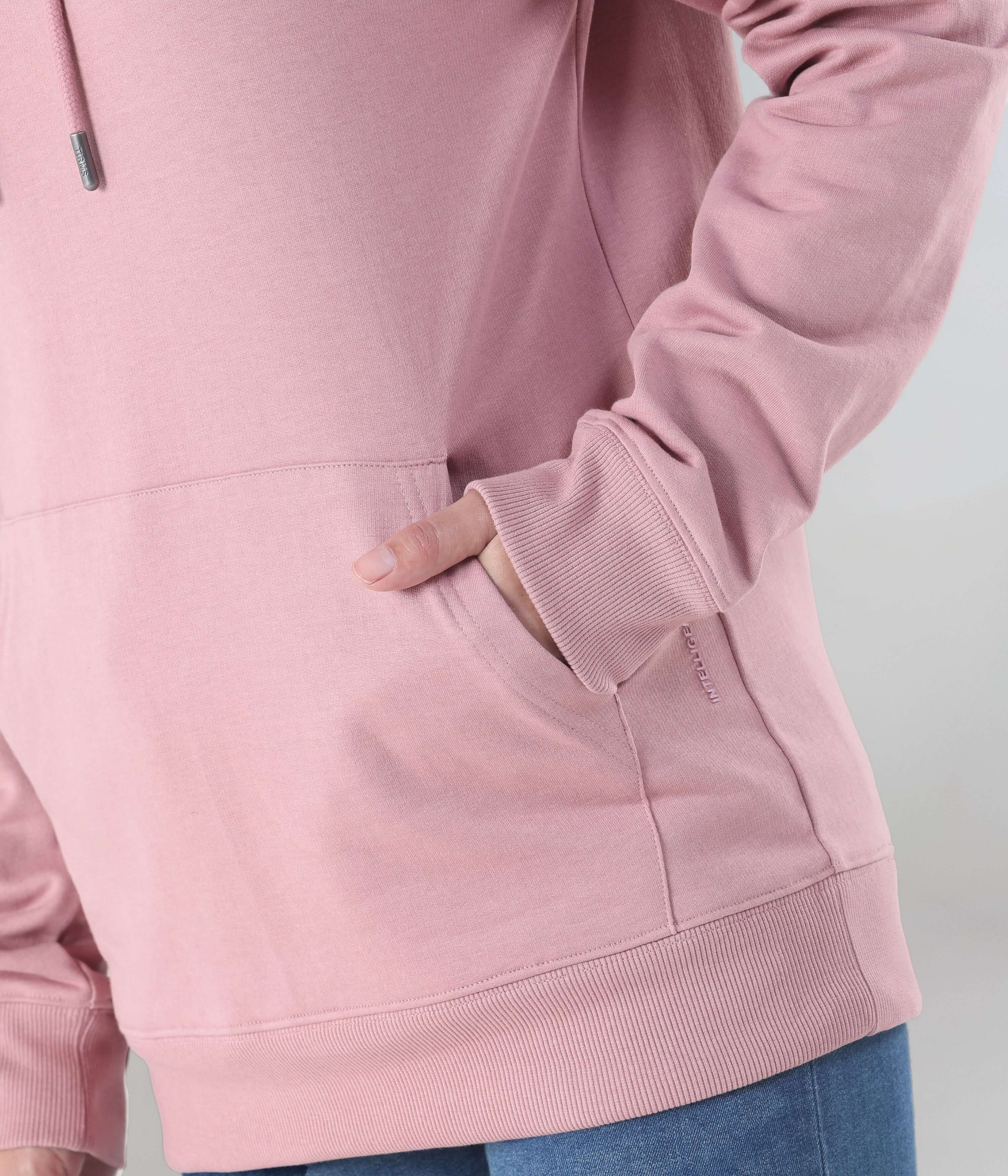 Close-up of a woman wearing the pink Turms Intelligent Hooded Sweatshirt, showcasing its soft fabric and convenient pockets.