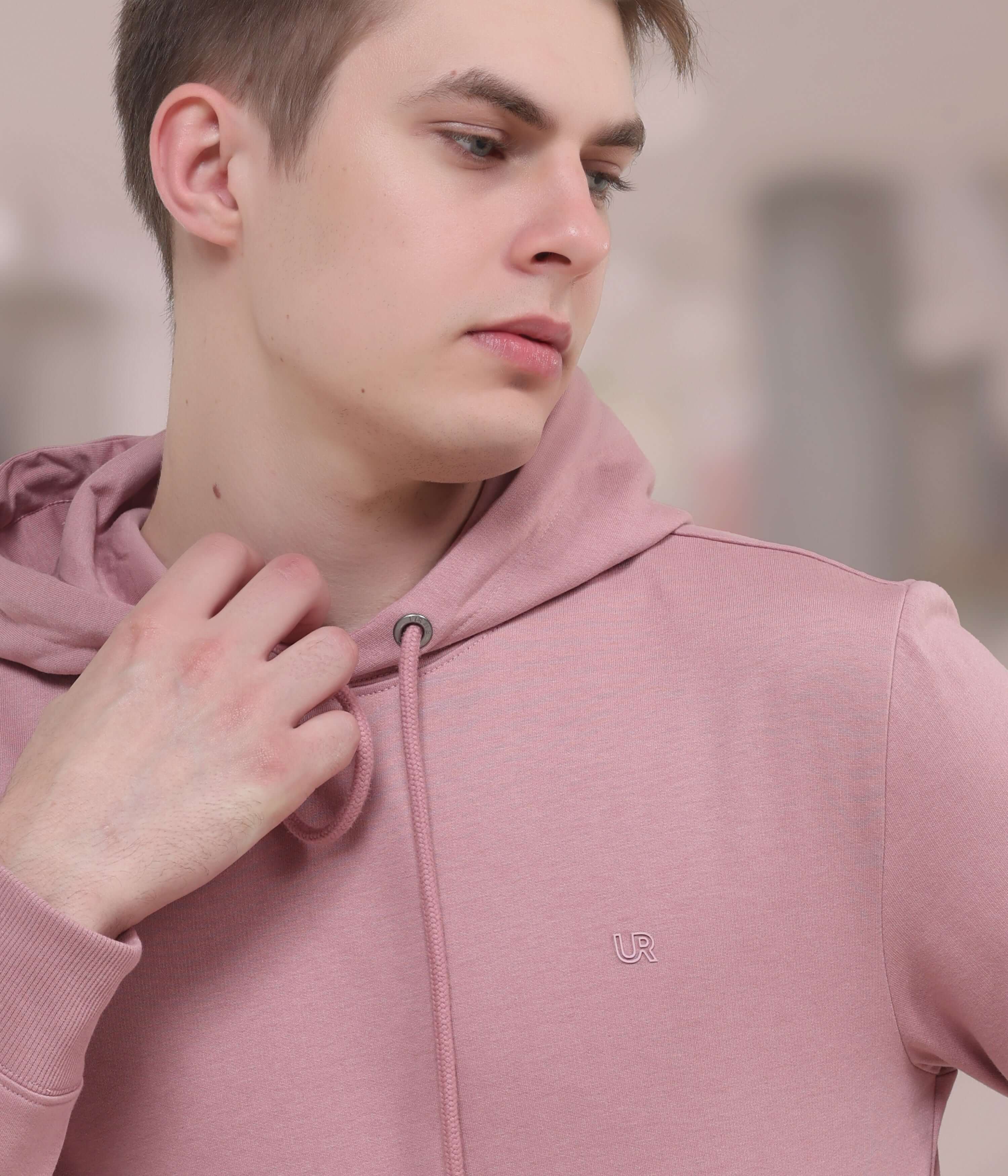 Model wearing a pink hooded sweatshirt, showcasing style and comfort in a modern setting.