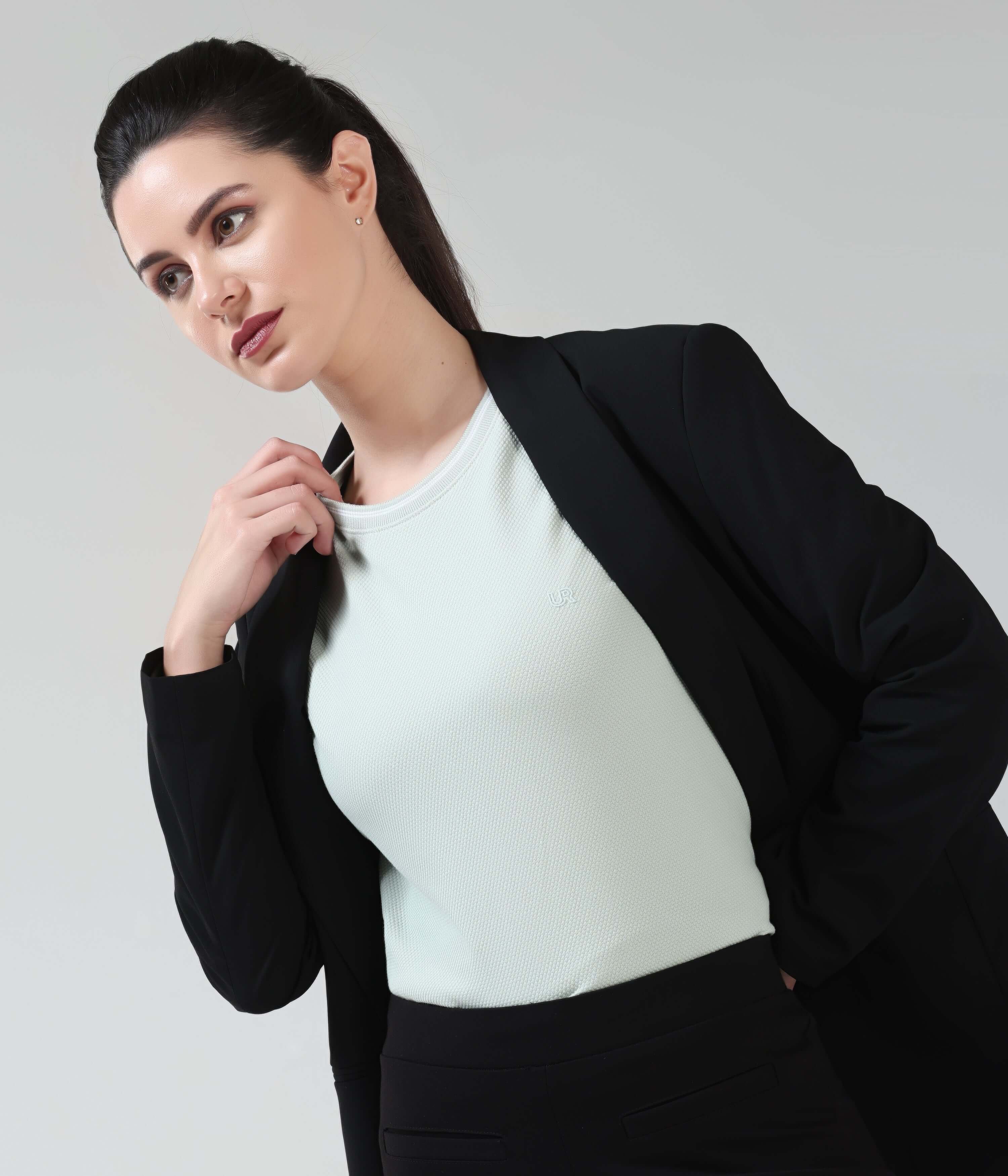 Woman wearing Serene Light Green COOLTECH T-shirt by Turms with black blazer, showcasing tailored fit and round neckline.