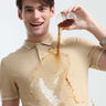 Man wearing a stylish Sandstone Turms Polo shirt with stain-repellent technology as liquid spills without staining the shirt.