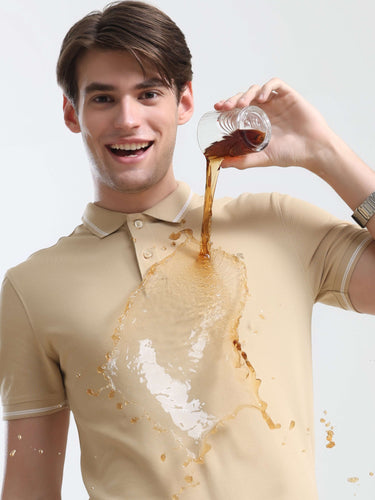 Man wearing a stylish Sandstone Turms Polo shirt with stain-repellent technology as liquid spills without staining the shirt.