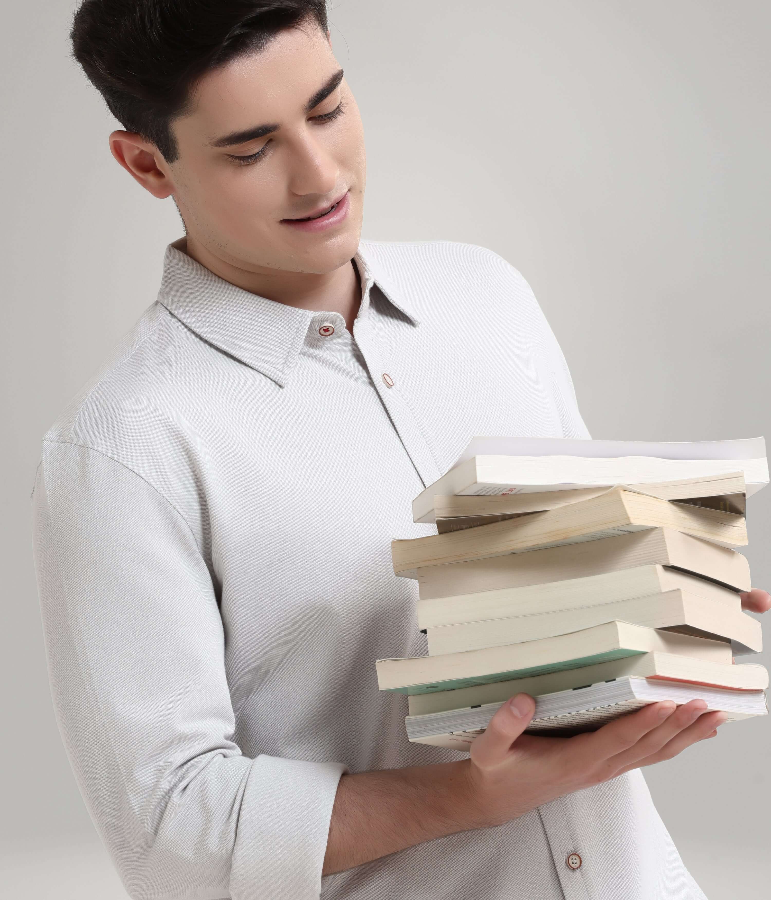 Man wearing Ashen Grey knitted shirt holding a stack of books, showcasing premium menswear style and stretchable comfort.