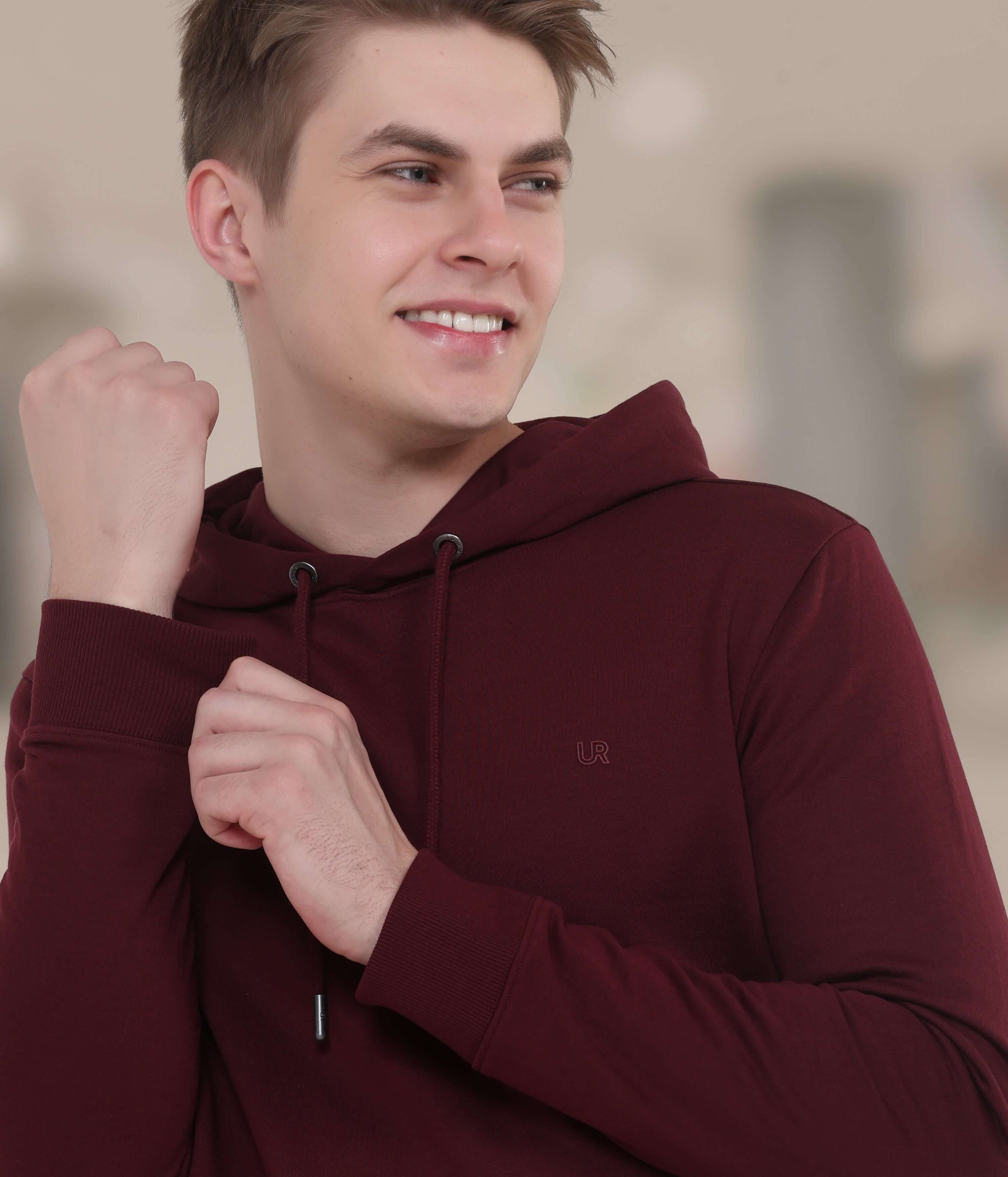 Young man wearing a maroon hooded sweatshirt, showcasing style and comfort in a modern design.