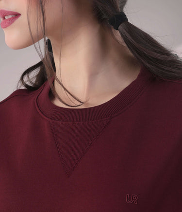 Close-up of a woman's burgundy sweatshirt featuring a stylish V-notch neckline, showcasing premium fabric and craftsmanship.