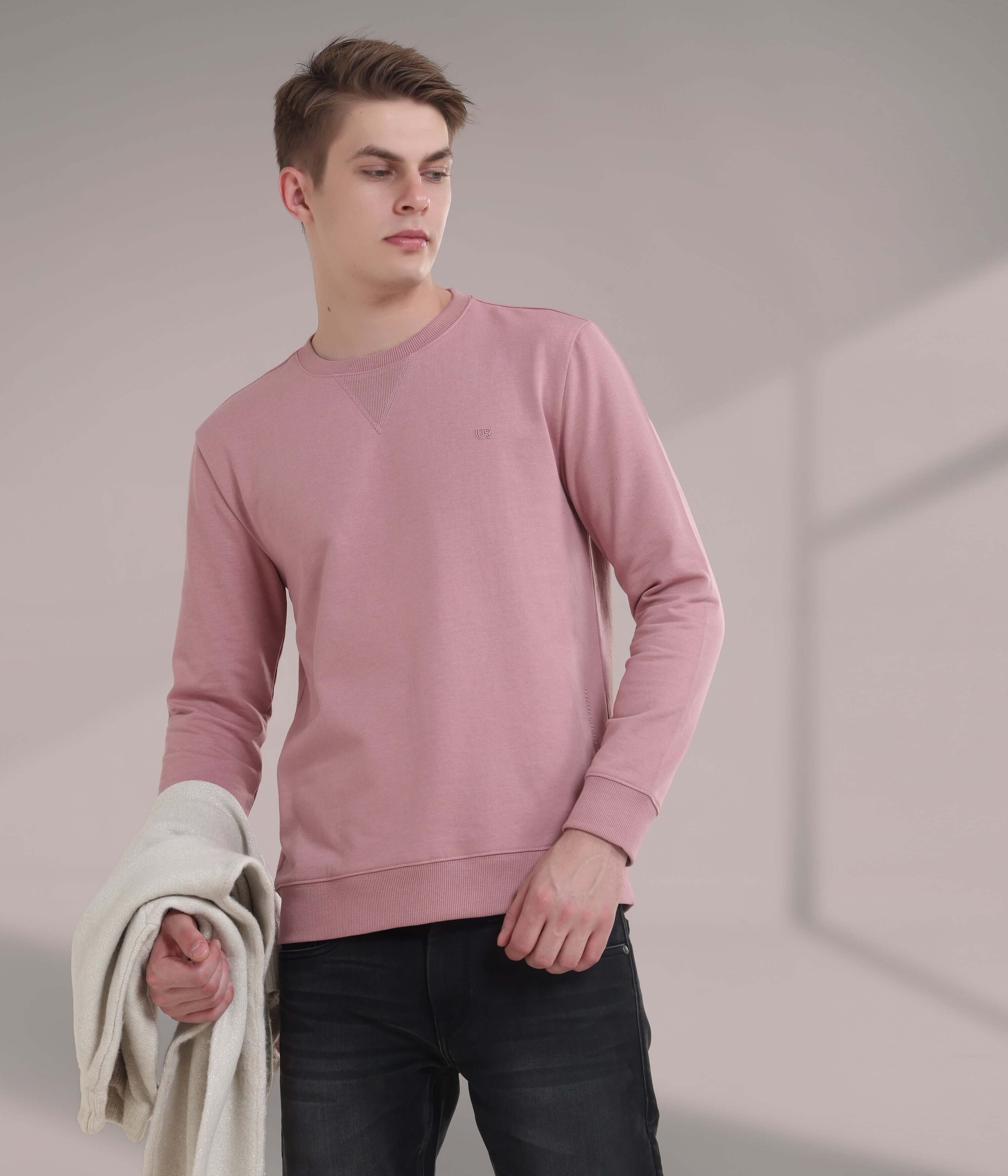 Young man wearing a pink sweatshirt, showcasing stylish water proof and anti-odour features in modern menswear.