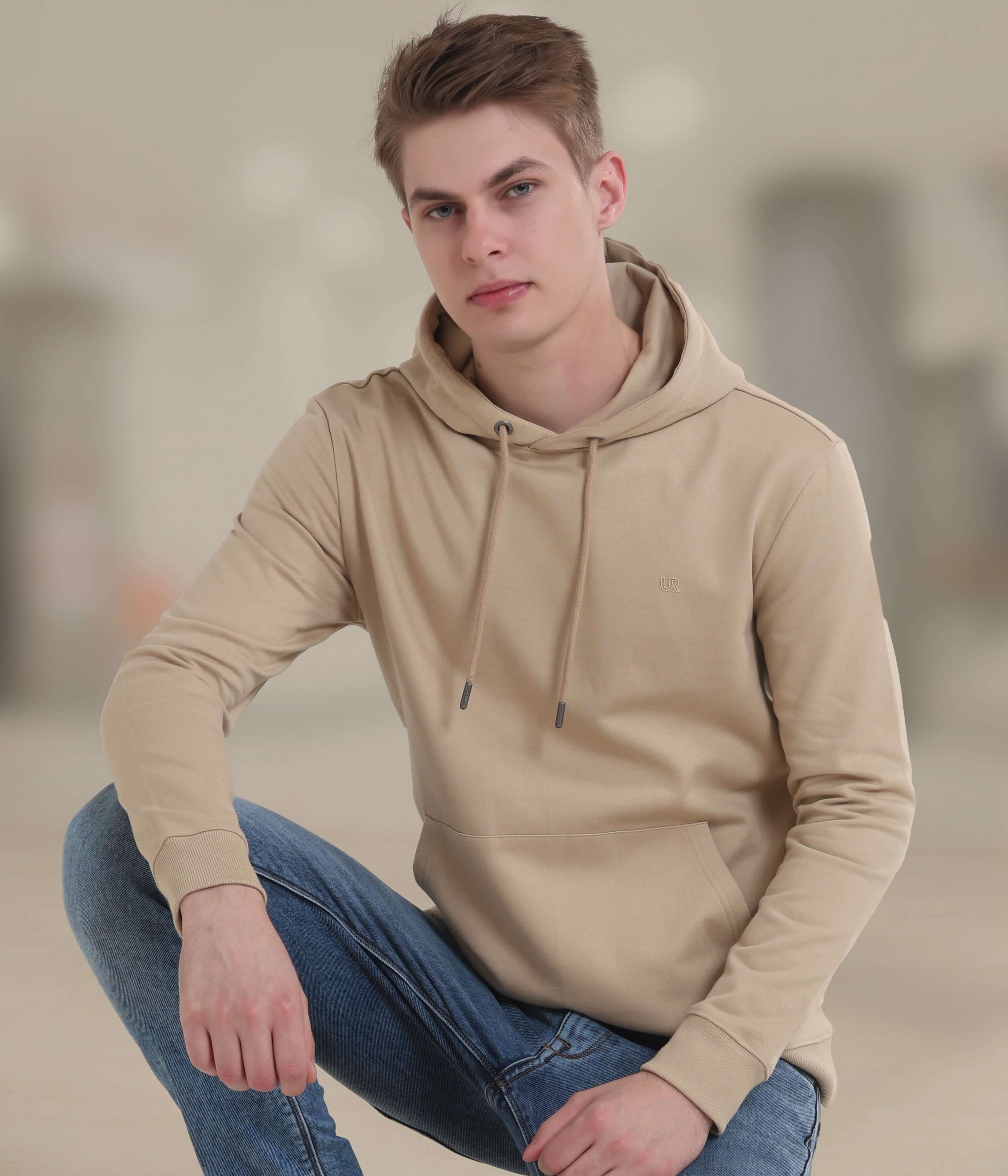 Young man wearing a camel-colored hooded sweatshirt, showcasing a blend of style and comfort in casual wear.