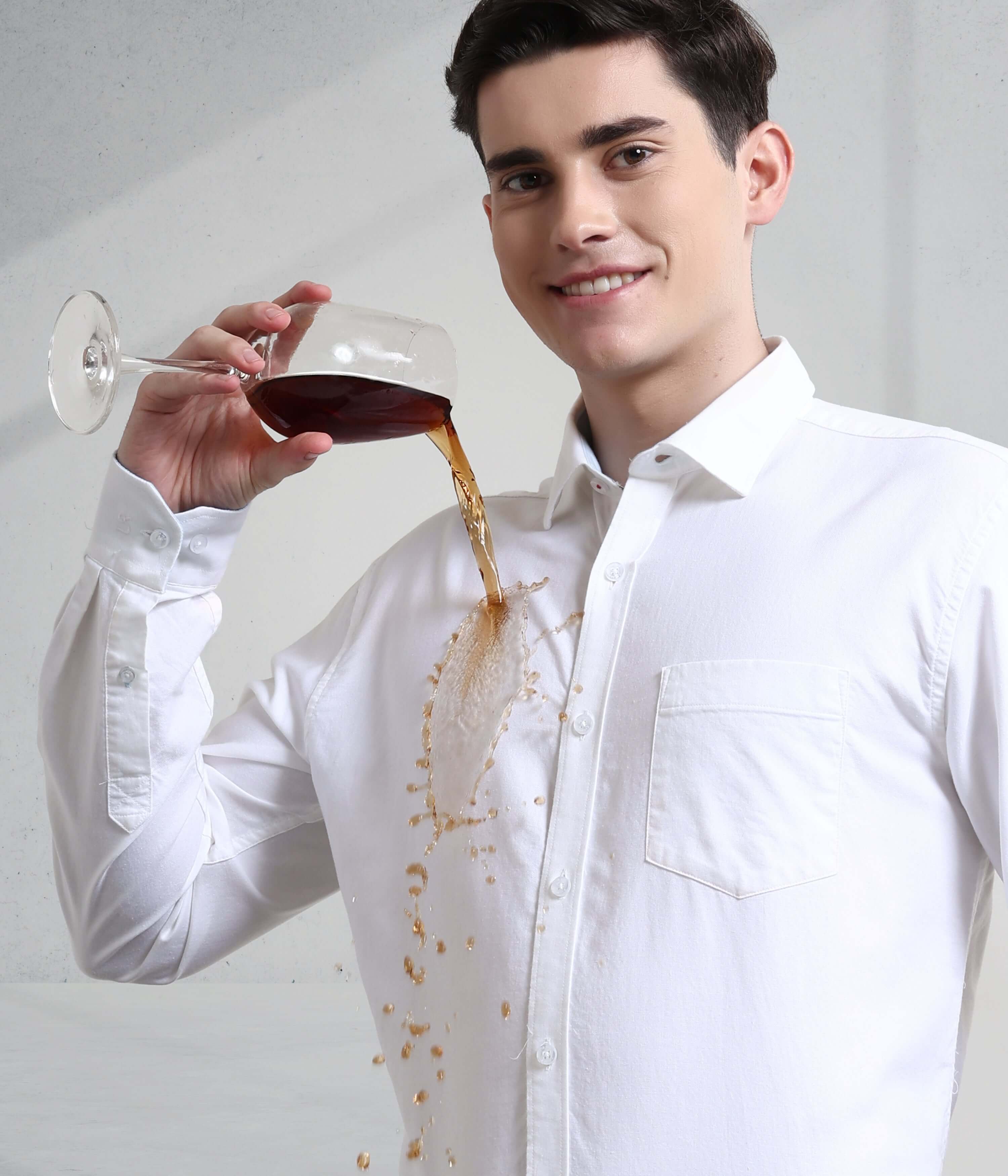 Man in white shirt demonstrating anti-stain feature with spilled drink, showcasing Toscana Lux Oxford Turms shirt's durability.